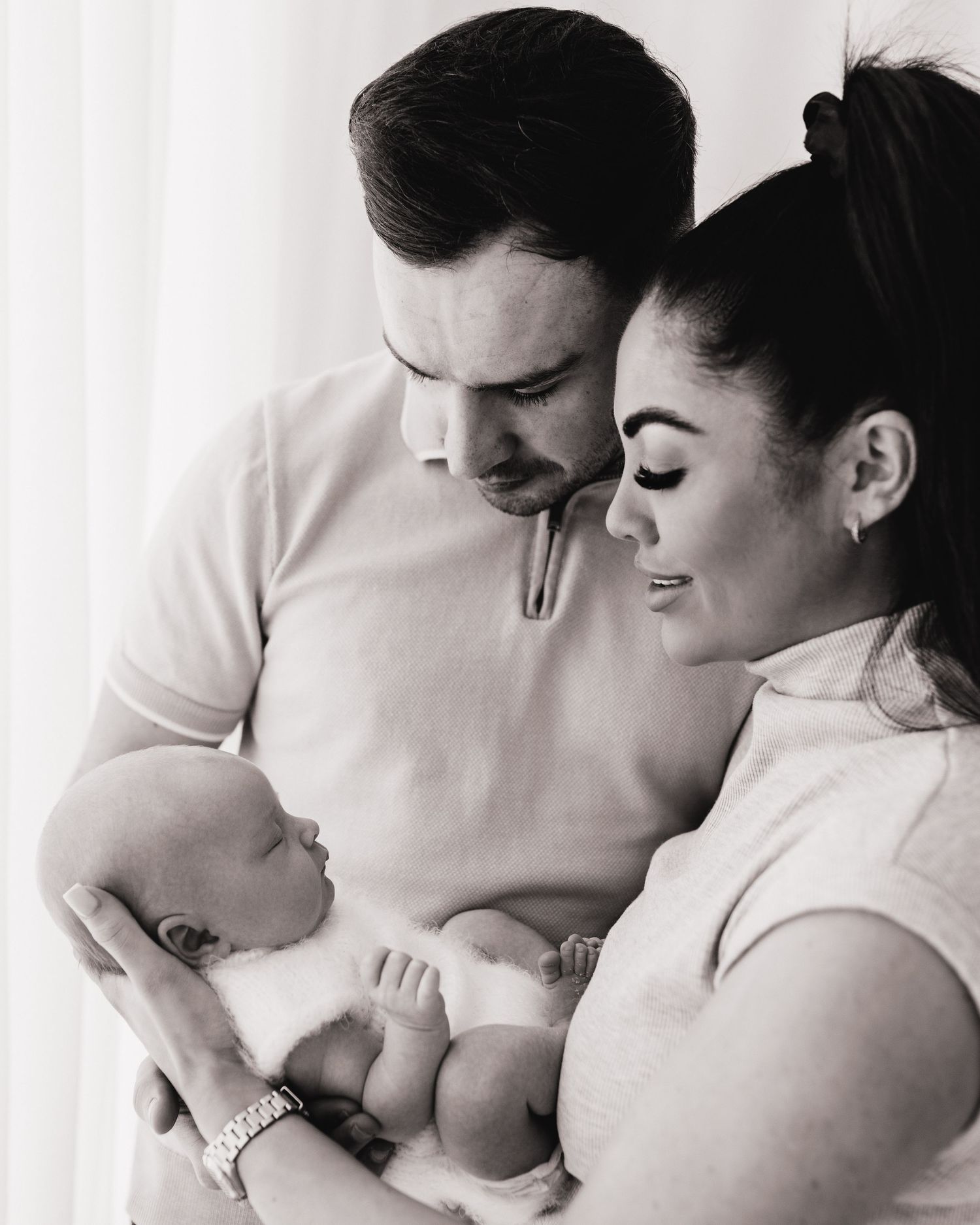 new parents gaze lovingly at the new baby girl, held in mums hands the quiet moment in Ayrshire studio is full of love