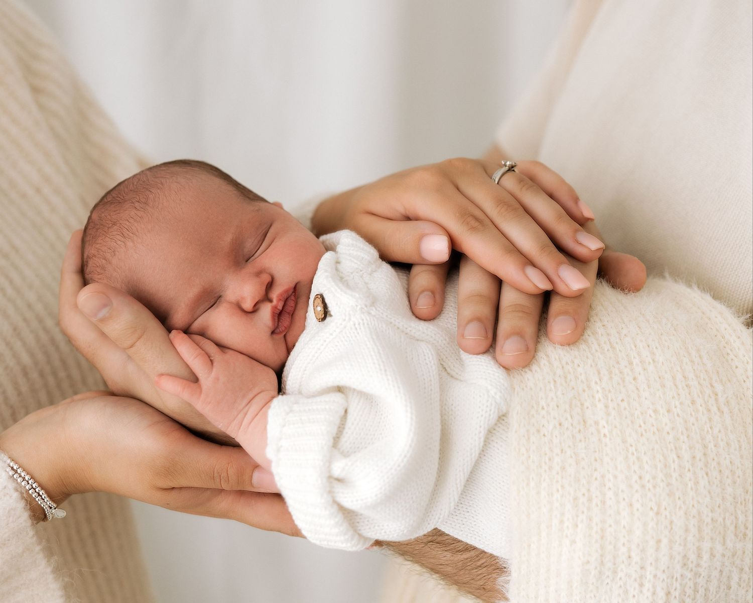 Newborn baby sleeping peacefully in parents’ hands during a natural newborn studio session in South Ayrshire