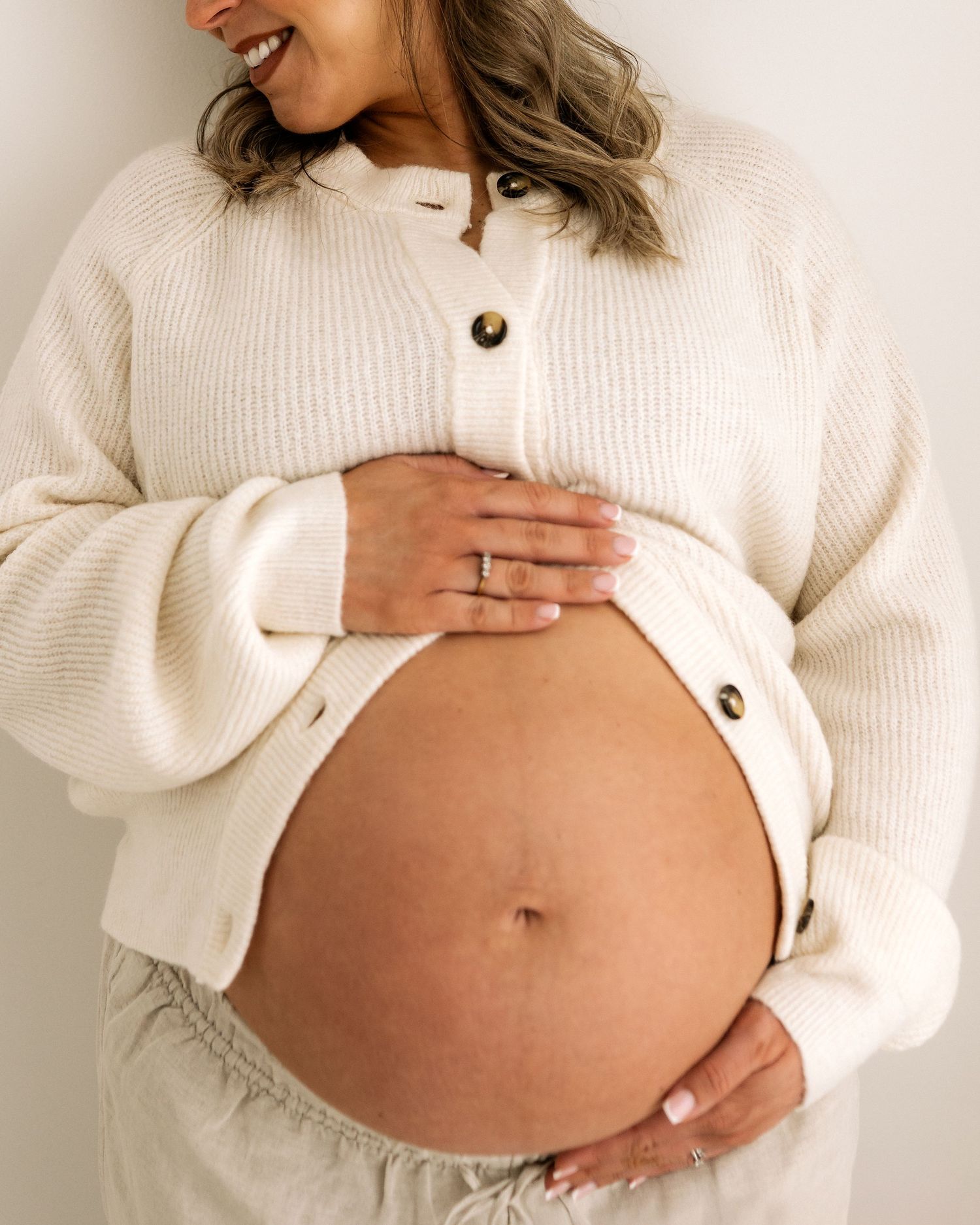 looking away from the camera laughing, this first time mum shows joy and excitement about what is to come, her hands cradling her bump