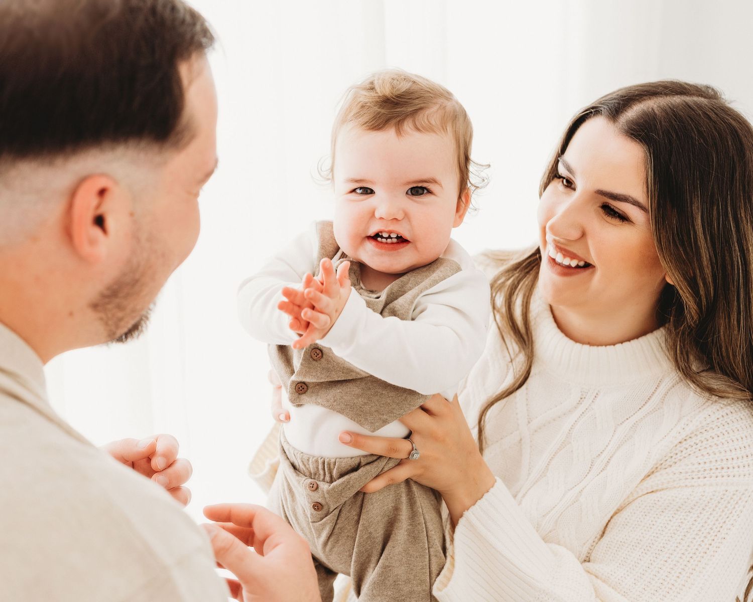 baby boy happily claps as his proud parents look on lovingly during his 1st birthday photoshoot with Faye McRae in South Ayrshire