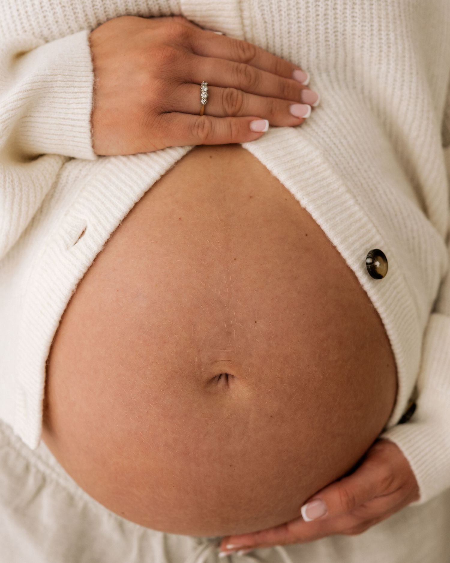 close up of mothers pregnant bump, her hands cradling the top and bottom signifying her immense love of her baby