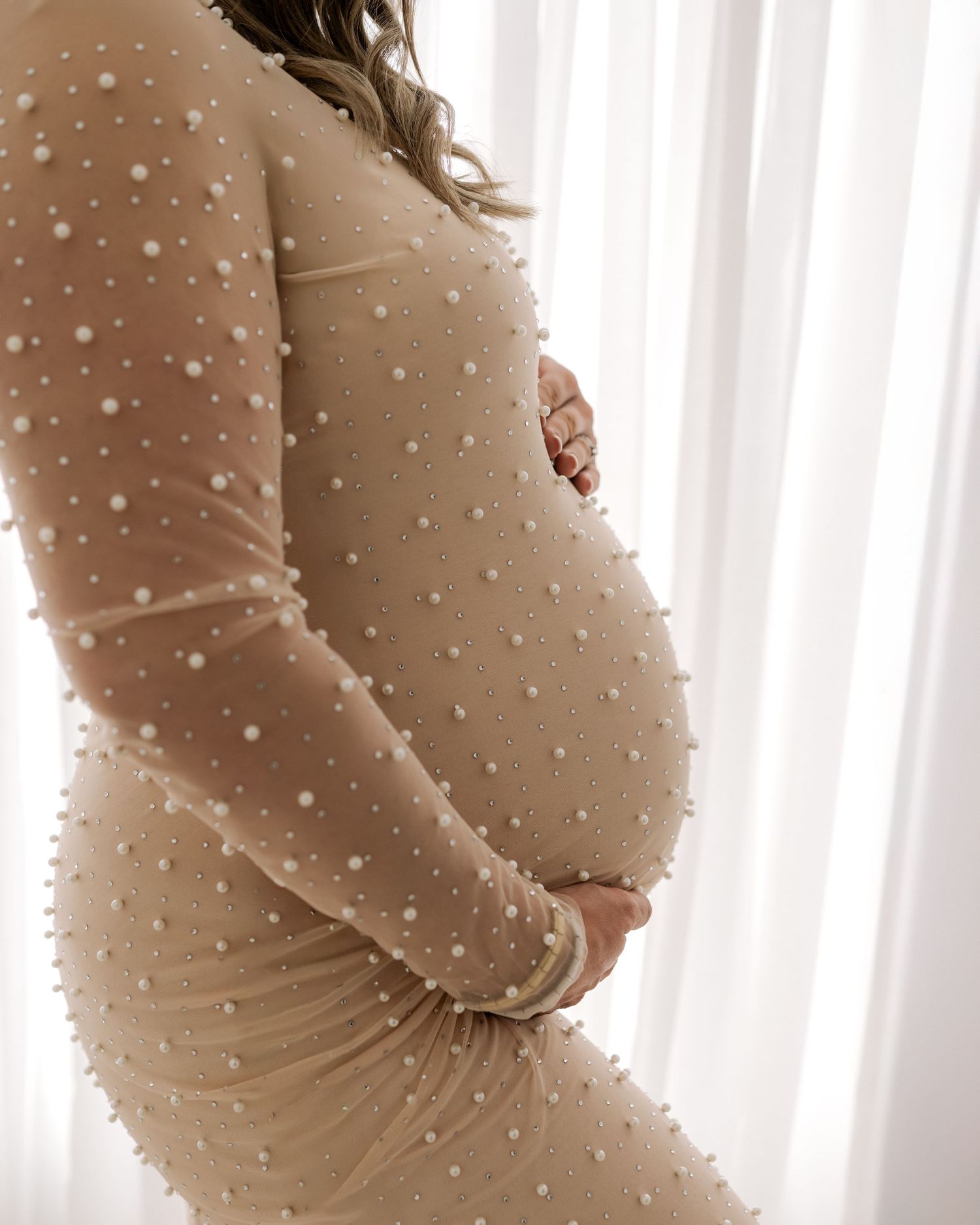Side profile of pregnancy bump captured in Faye McRae's natural Ayrshire studio, the expectant mothers hands gently cradling her bump