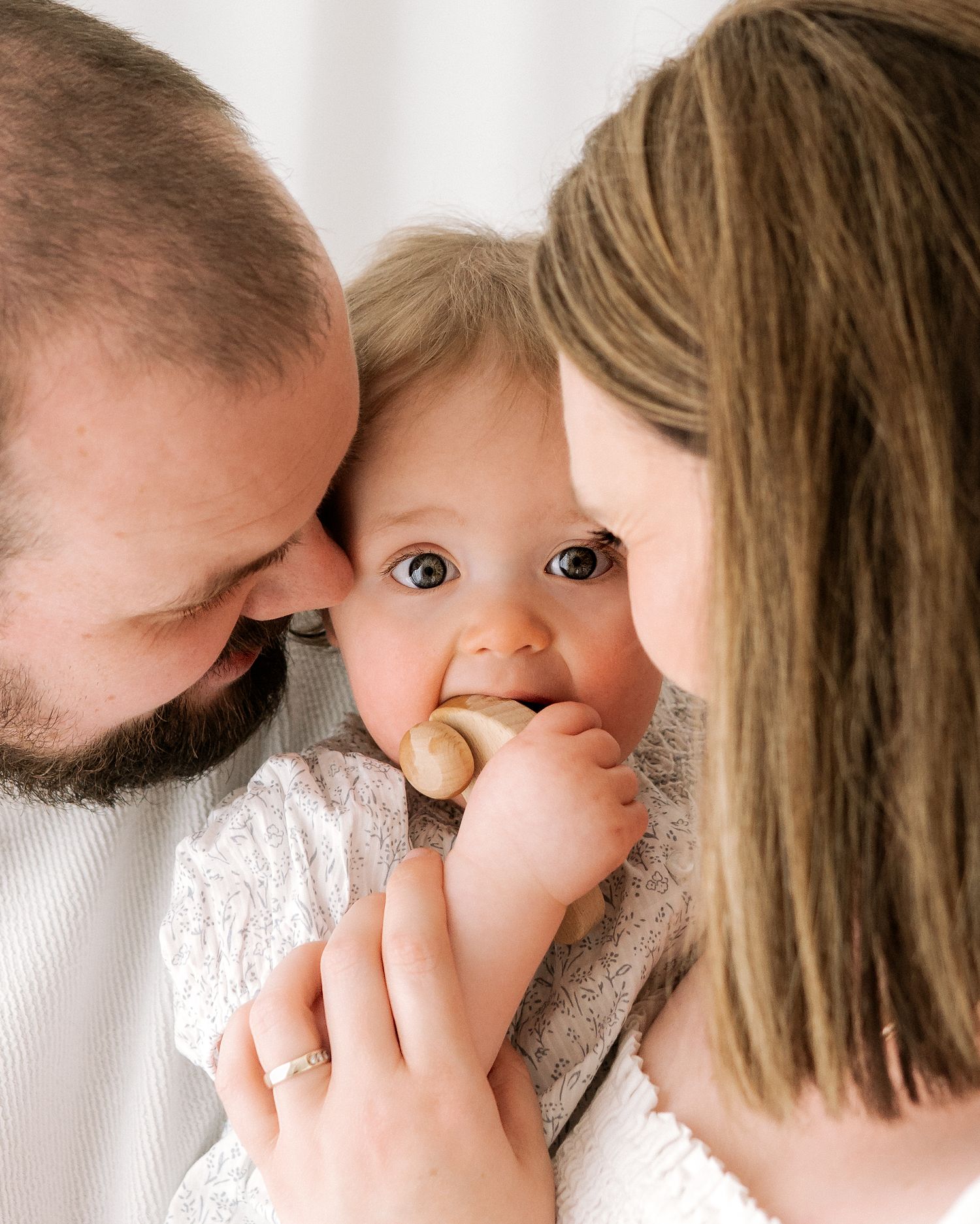 the baby looks directly into the camera as her doting parents gaze at their beautiful baby celebrating her turning 1 in her milestone shoot