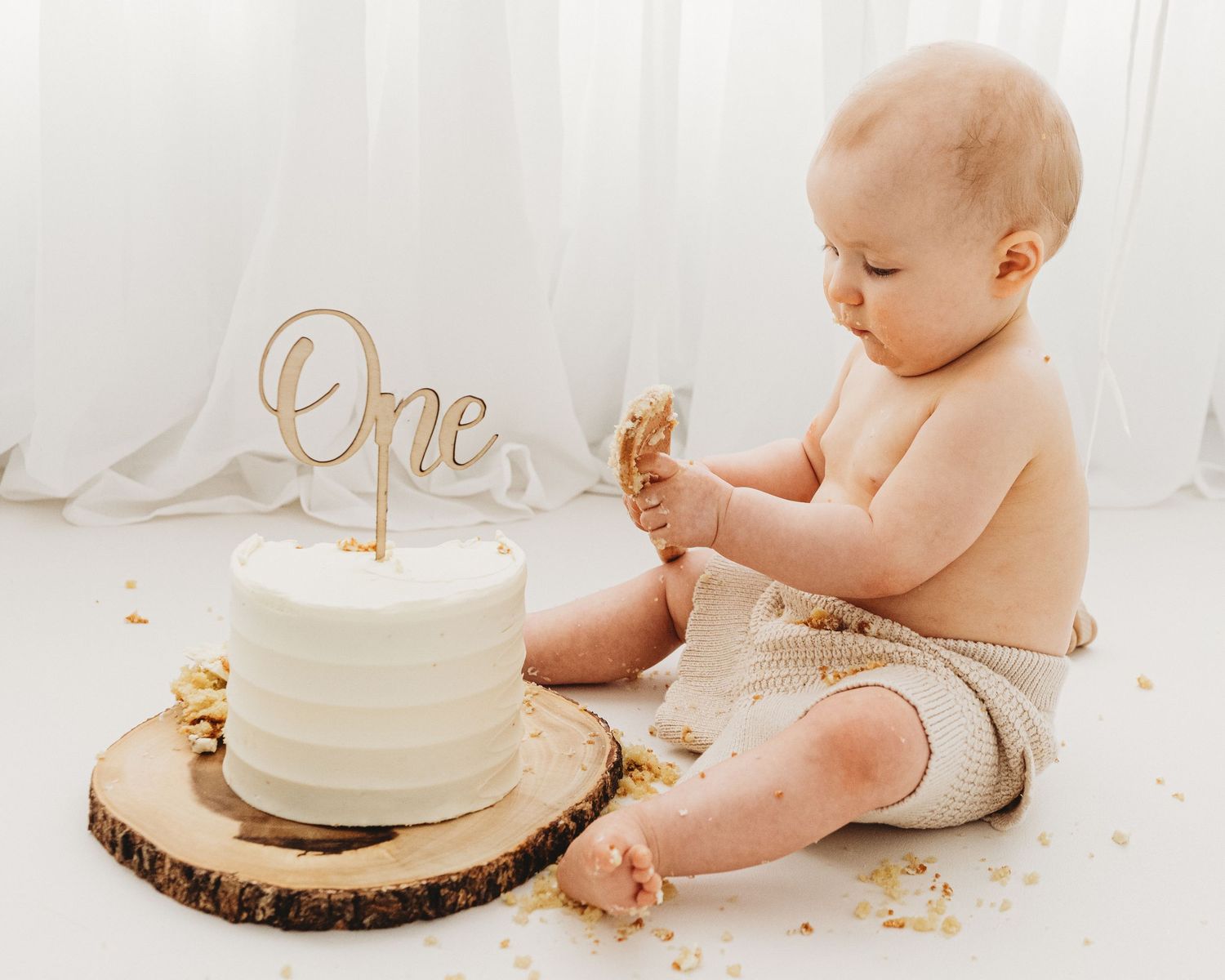 Enjoying celebrating turning 1, this candid moment captures the baby smashing their cake in Ayrshire's all-white studio