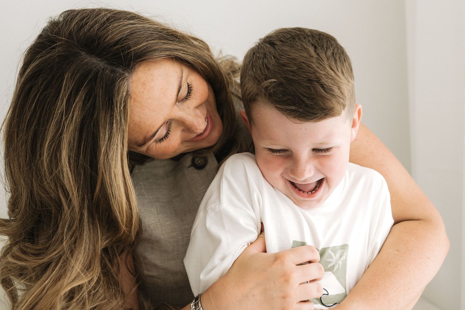 mum tickles her 5 year old son who giggles naturally and the moment is captured beautifully and naturally