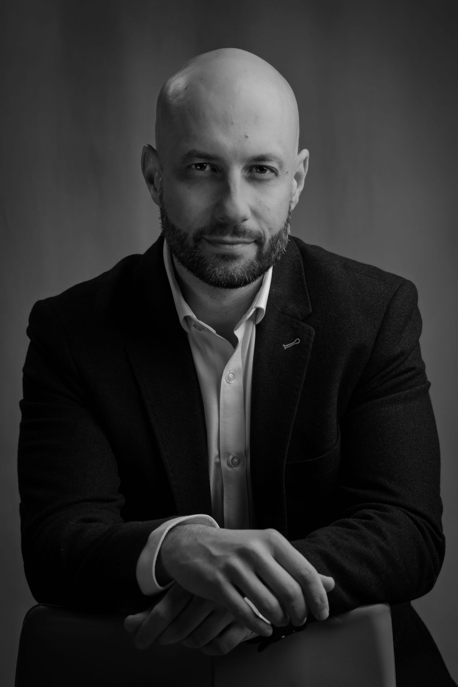 Professional black and white portrait series showing different angles of a person in a dark suit against a studio backdrop.