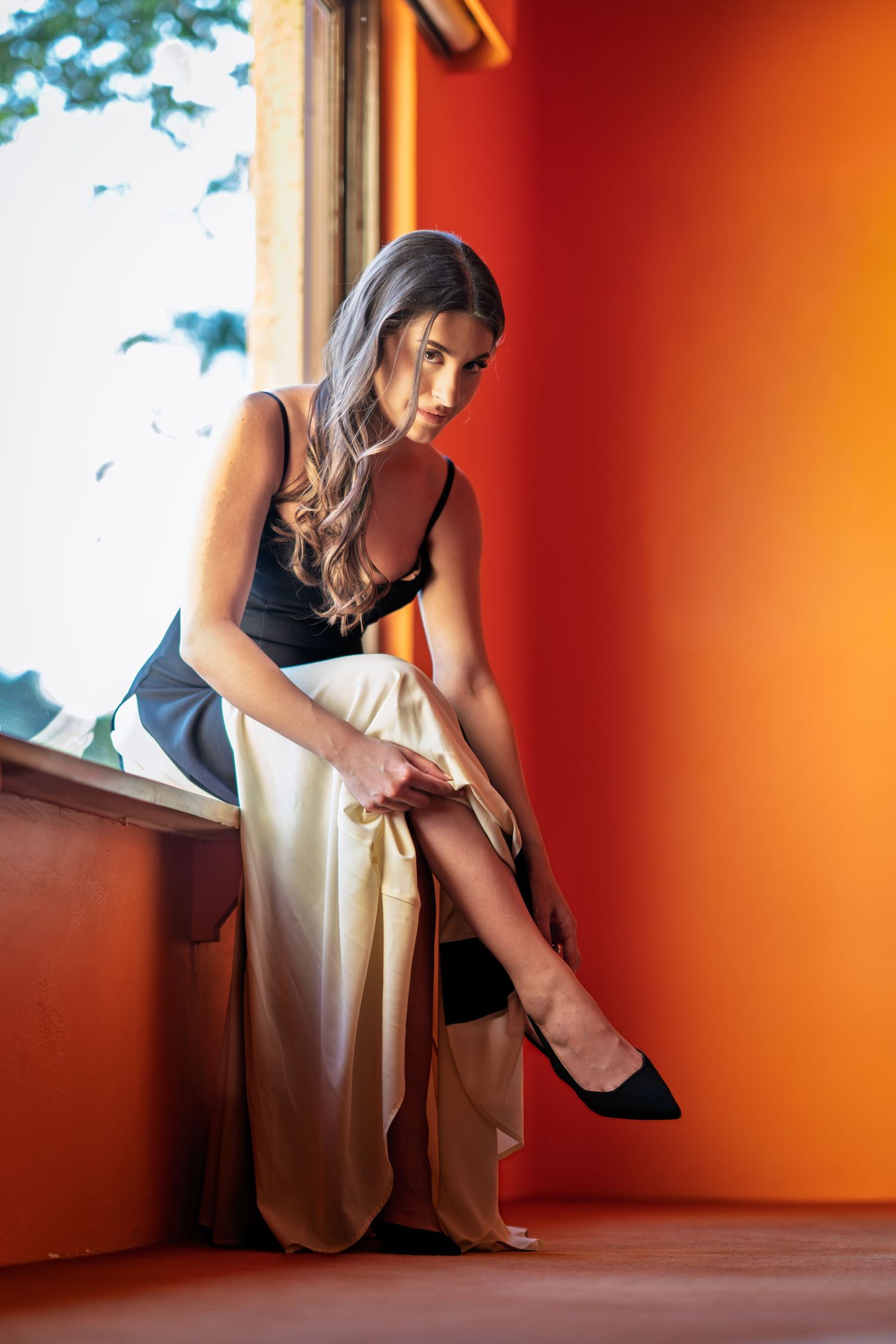 Artistic fashion photo sequence showing movement against an orange wall with window light.