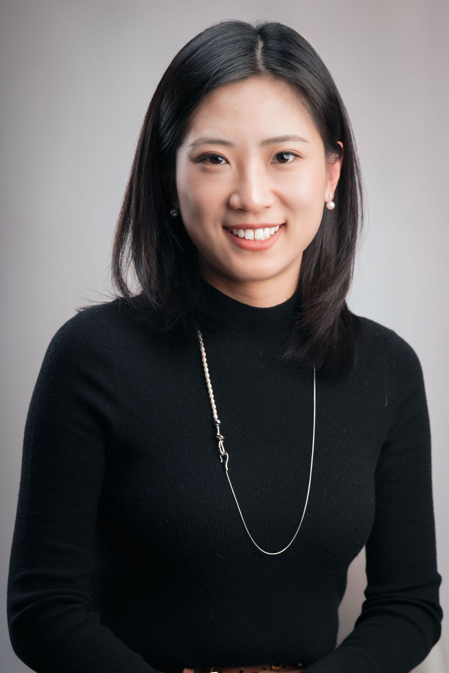 A series of portraits showing someone in a black turtleneck sweater and silver necklace against a light gray background.