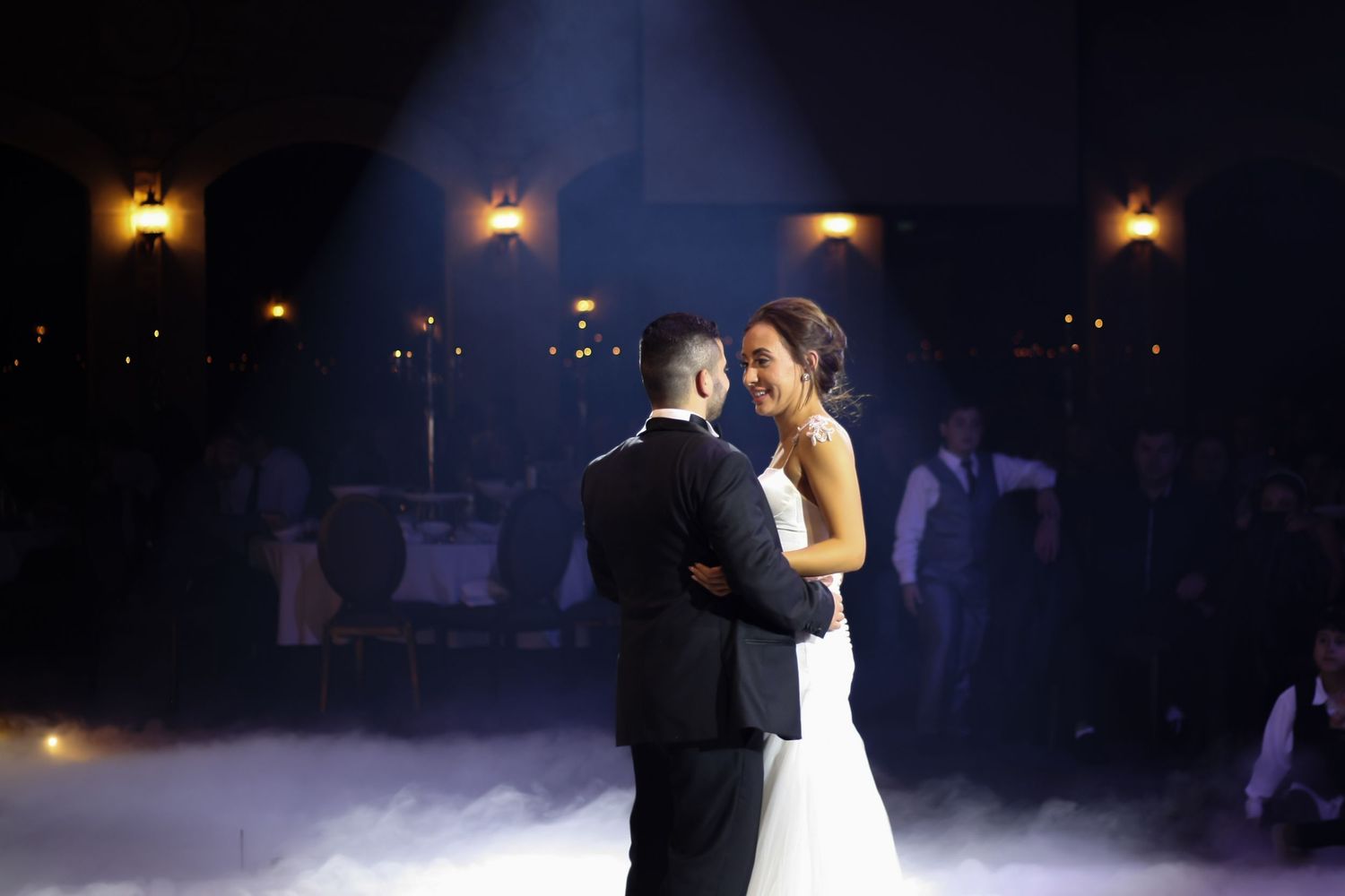 Romantic first dance at a wedding reception with dramatic lighting and fog effects.