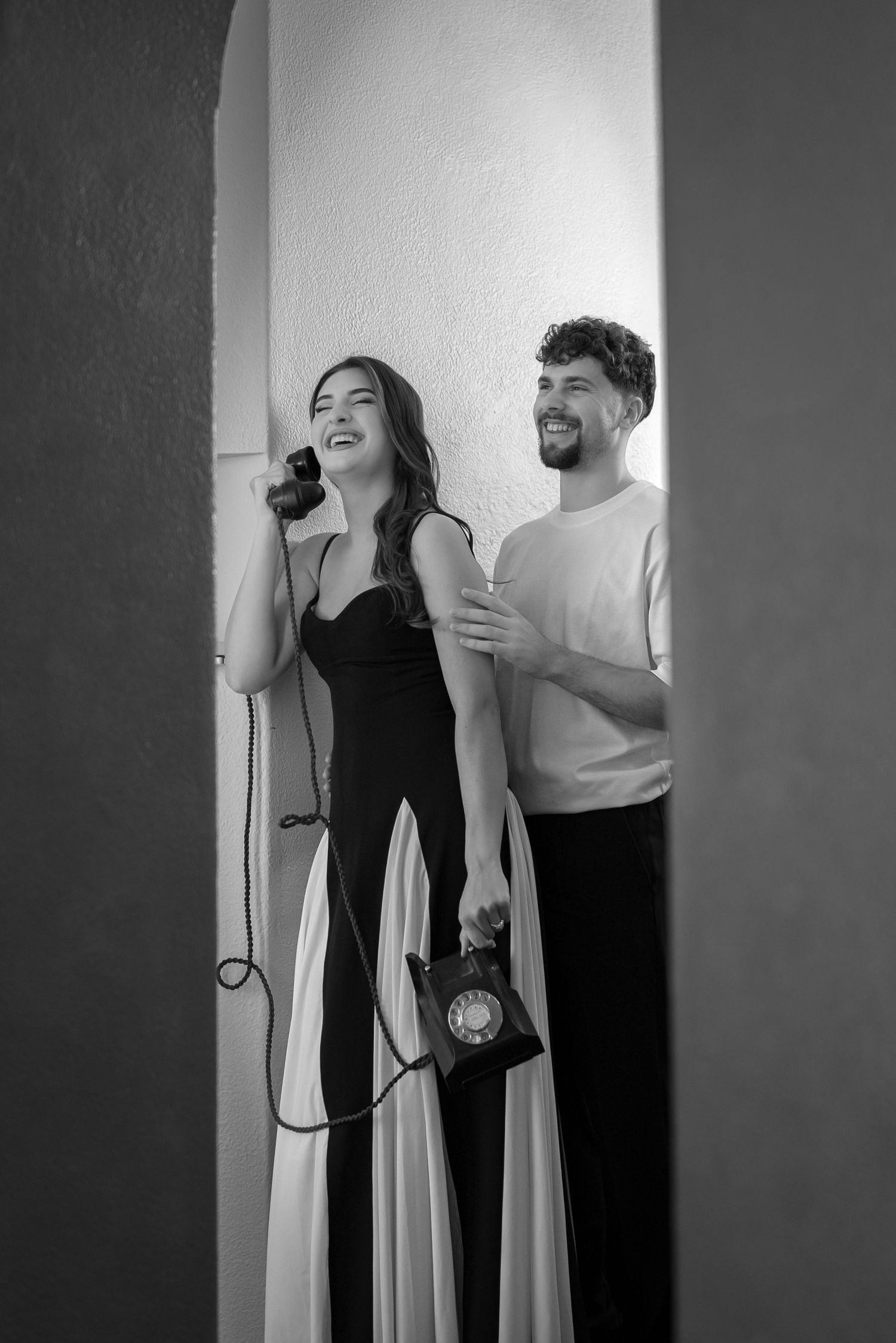 A black and white photo of two people laughing together, one in a dark dress and one in a light sweater.