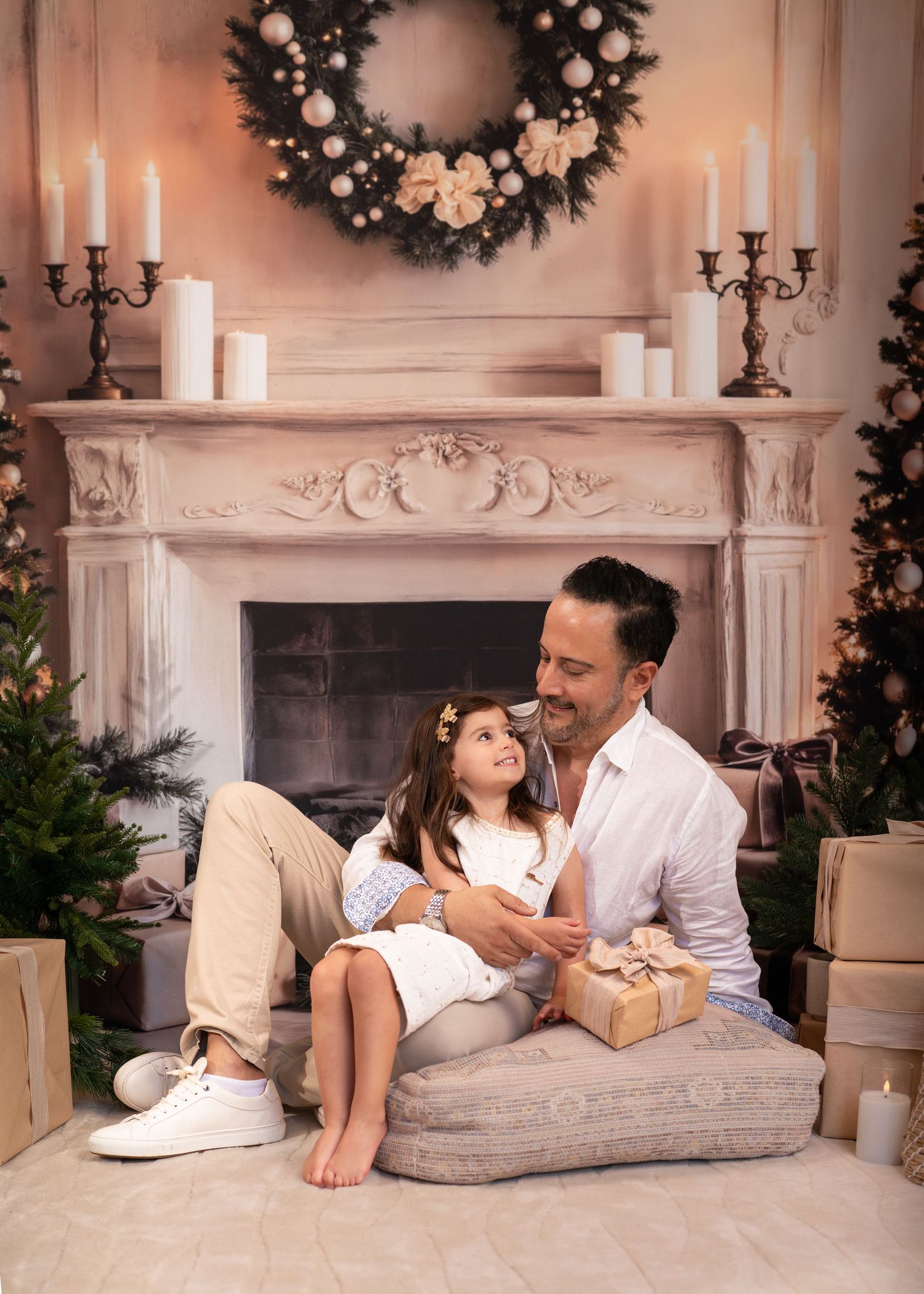 Couple relaxes together on a cozy floor cushion by a decorated Christmas fireplace with wreaths and candles.