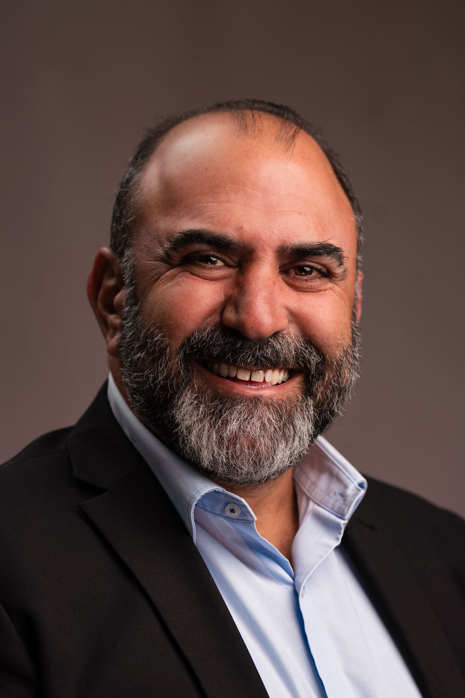 Professional studio portrait of a man in business attire with a full beard showing different expressions.