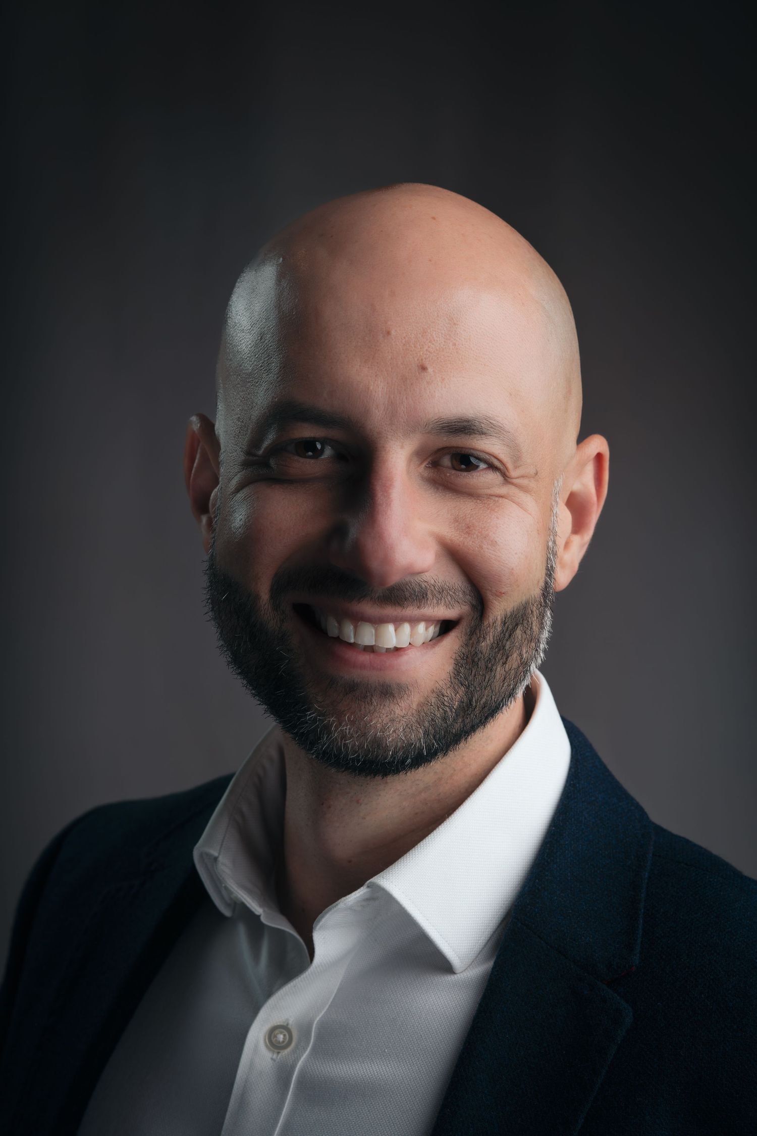 Professional headshots in moody lighting show a smiling person in business attire against dark background.