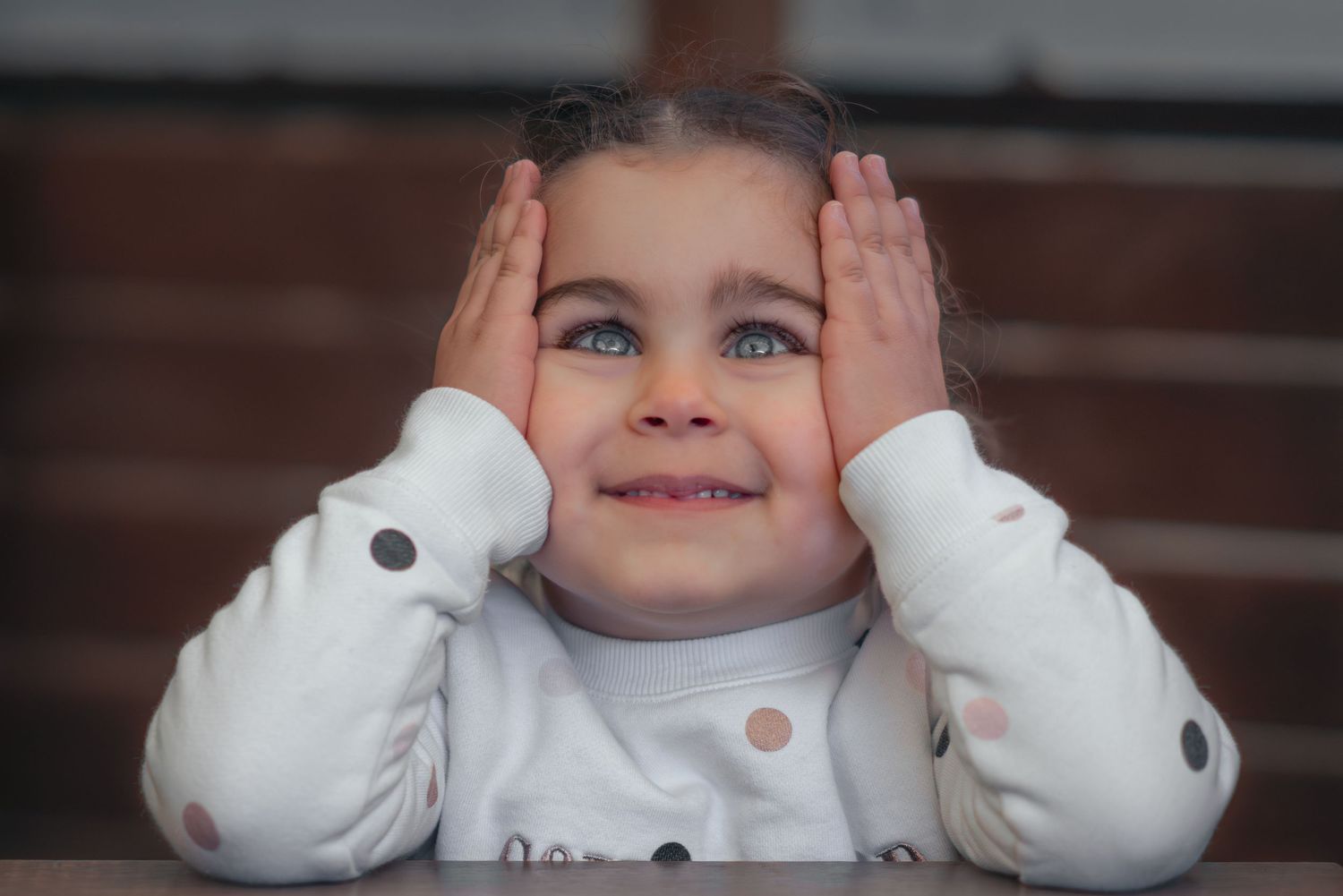 Baby dressed in white sweater going through range of playful expressions and poses.