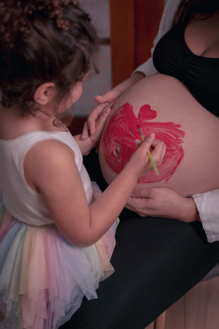 Drawing a heart on a pregnant belly in a touching maternity moment.