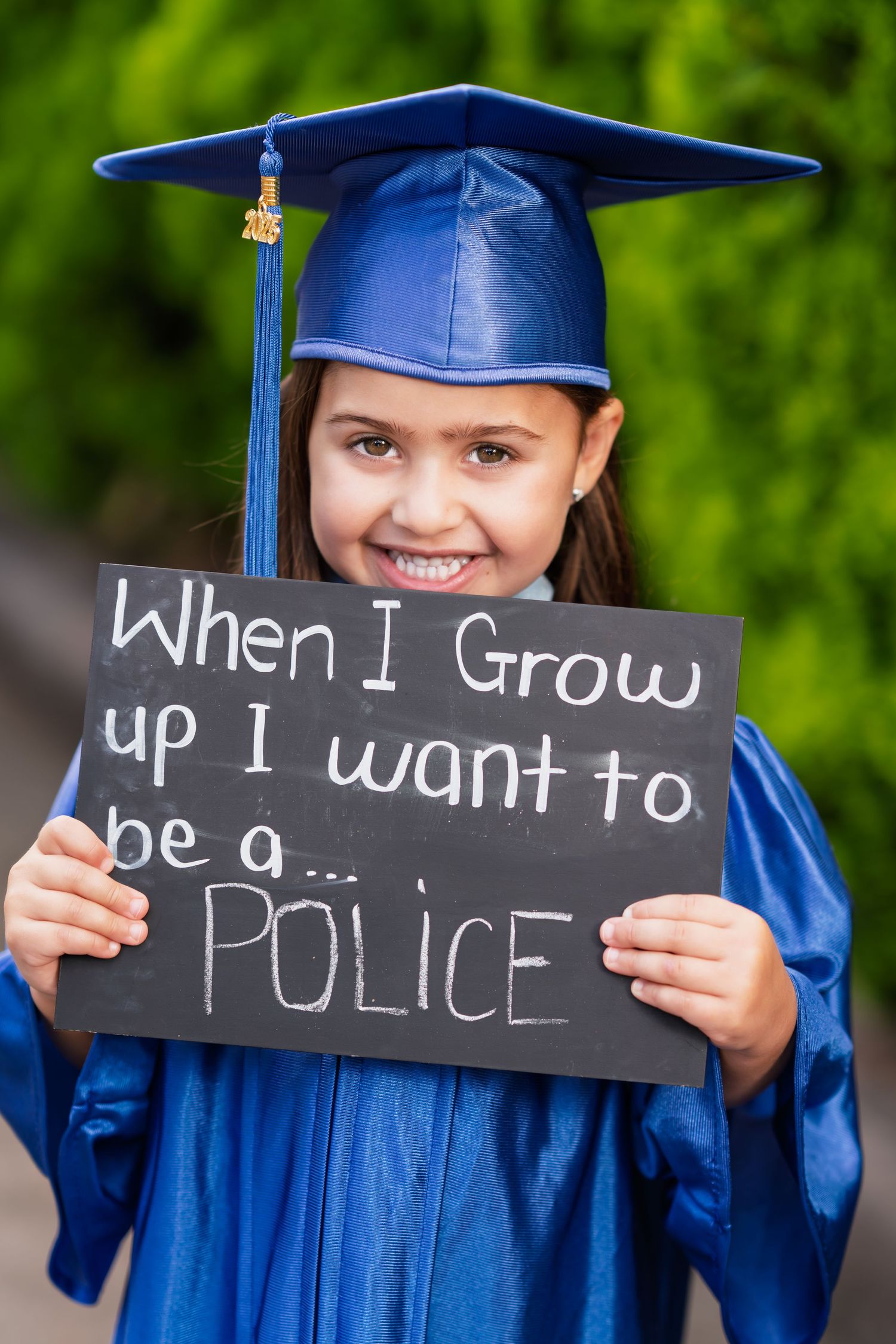 A graduation photo series showing blue cap and gown with chalkboard signs spelling out 'When I grow up I want to be a police'.
