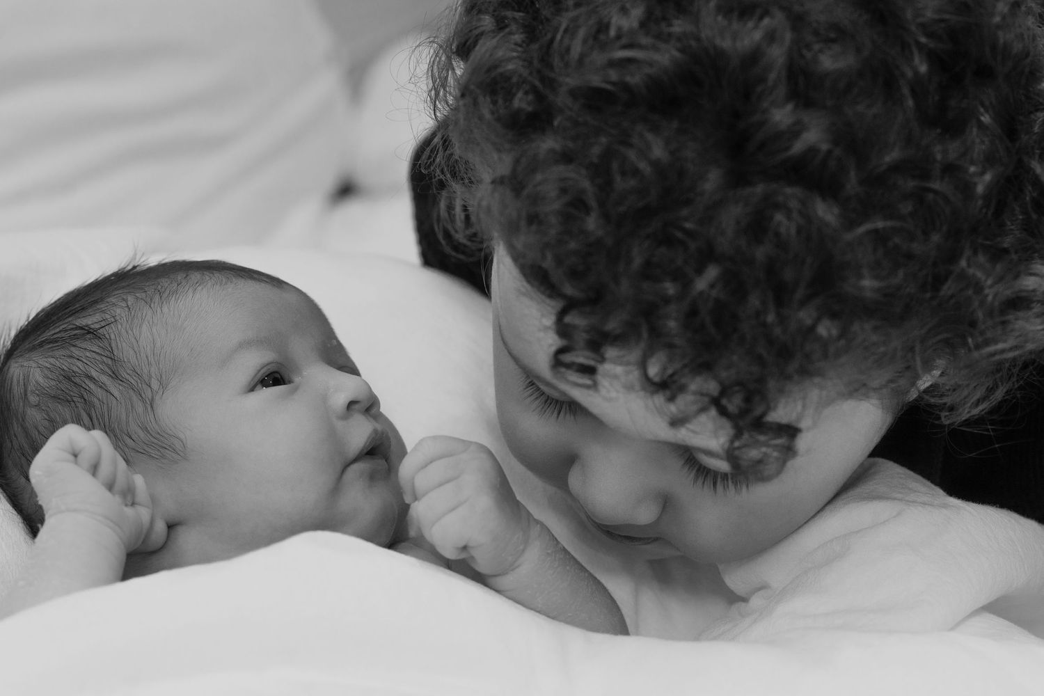 Intimate black and white portrait of two figures sharing a tender moment.