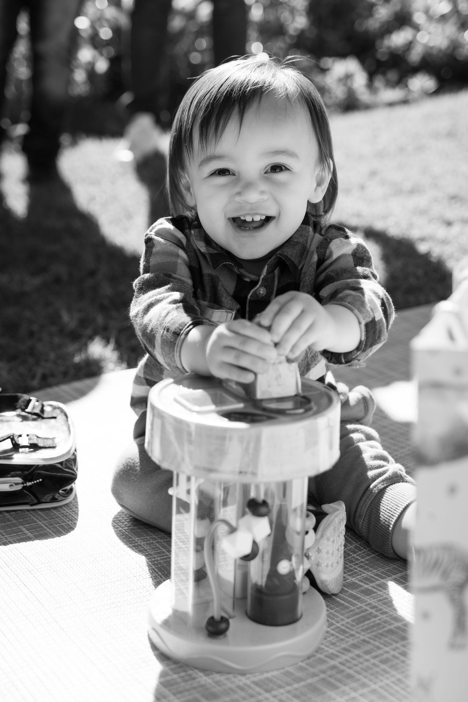 A child plays with a clear toy container outdoors in black and white photography.