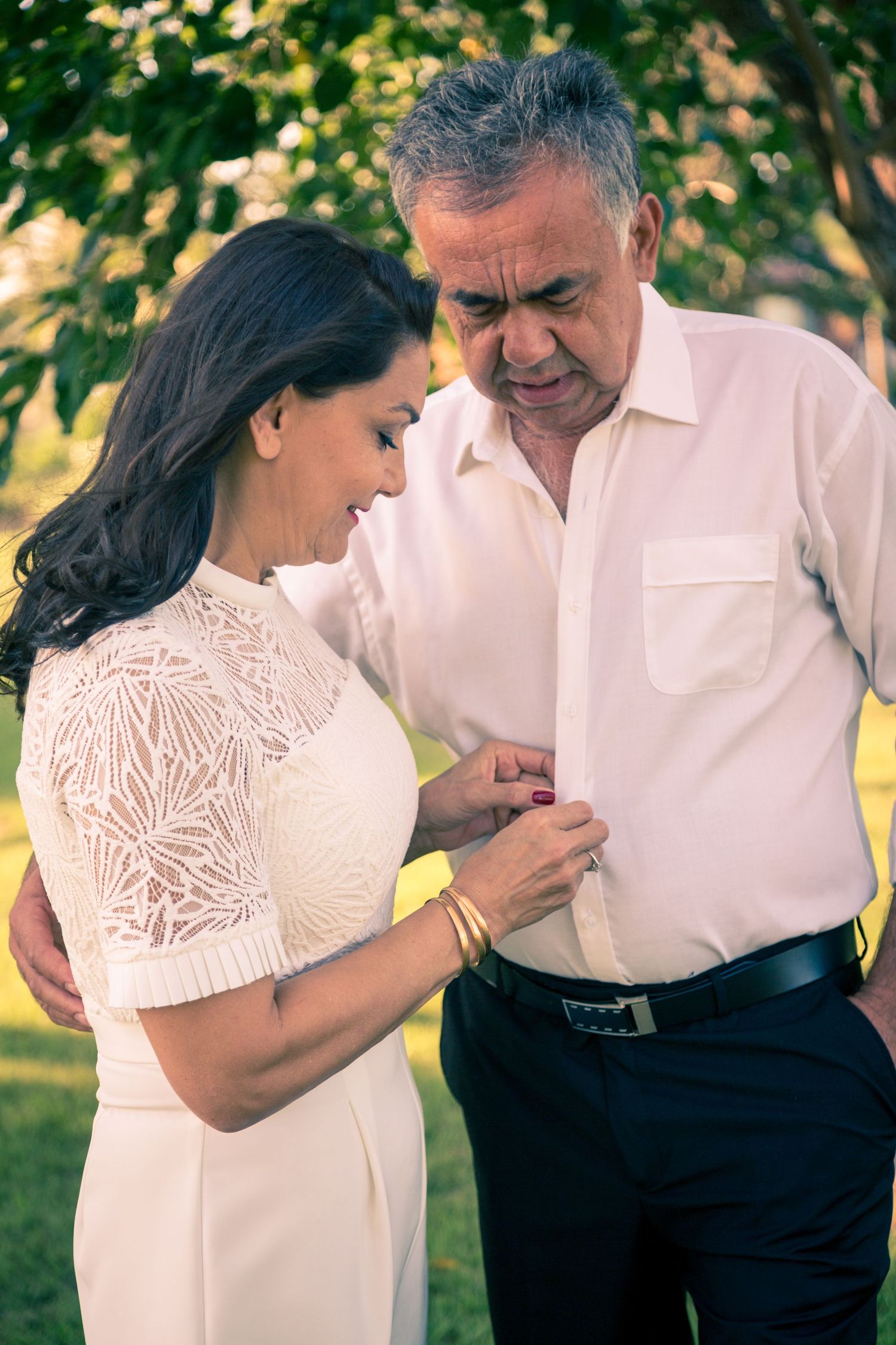 Candid outdoor couple photos showing tender moments in white formal attire.