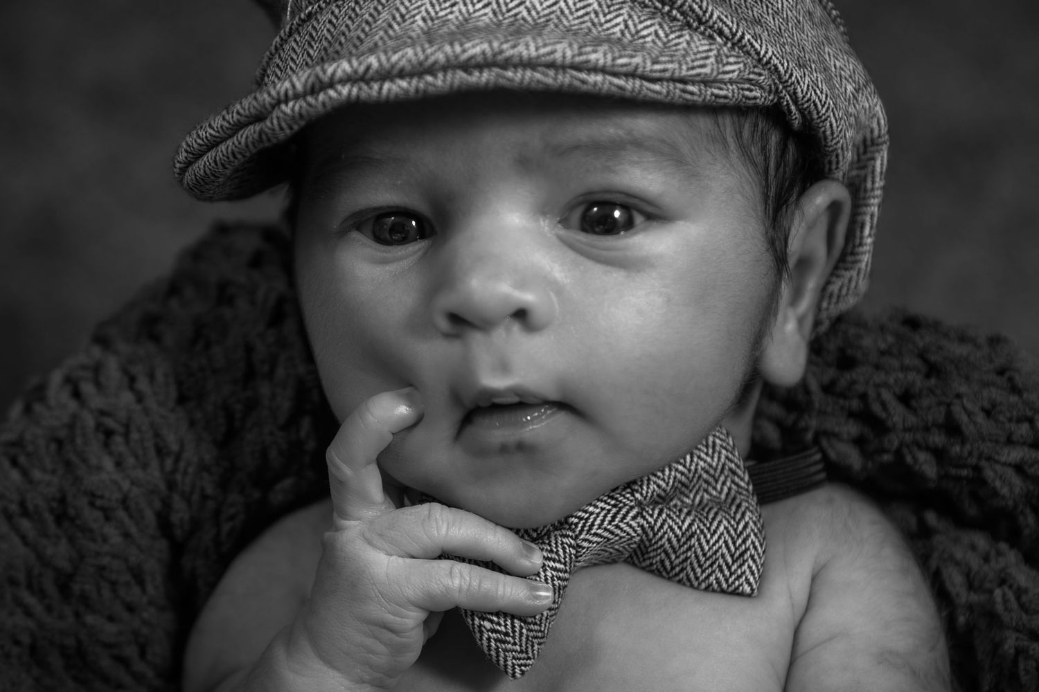 Baby wearing vintage newsboy cap in black and white portrait.
