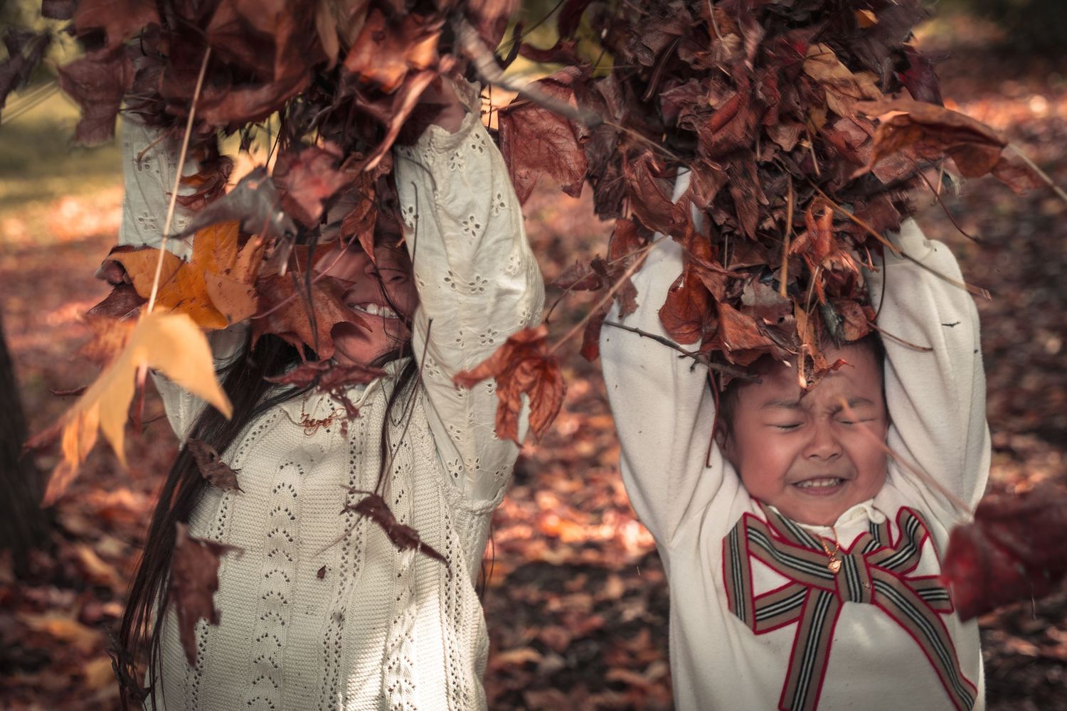 A series of six candid autumn photos showing someone sitting and playing in a pile of fallen orange leaves.
