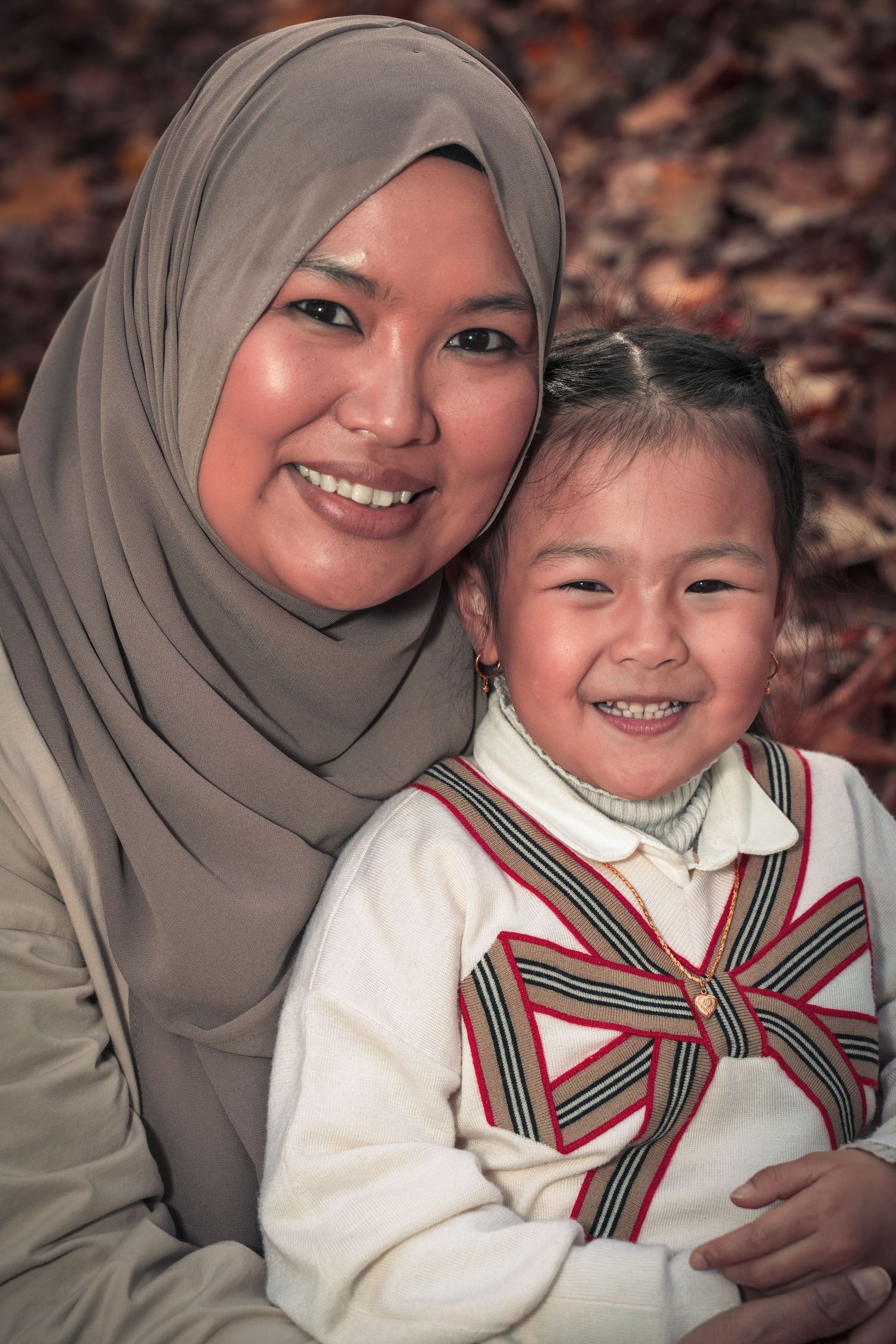 Two people sharing a warm embrace and smile while posing outdoors in autumn.