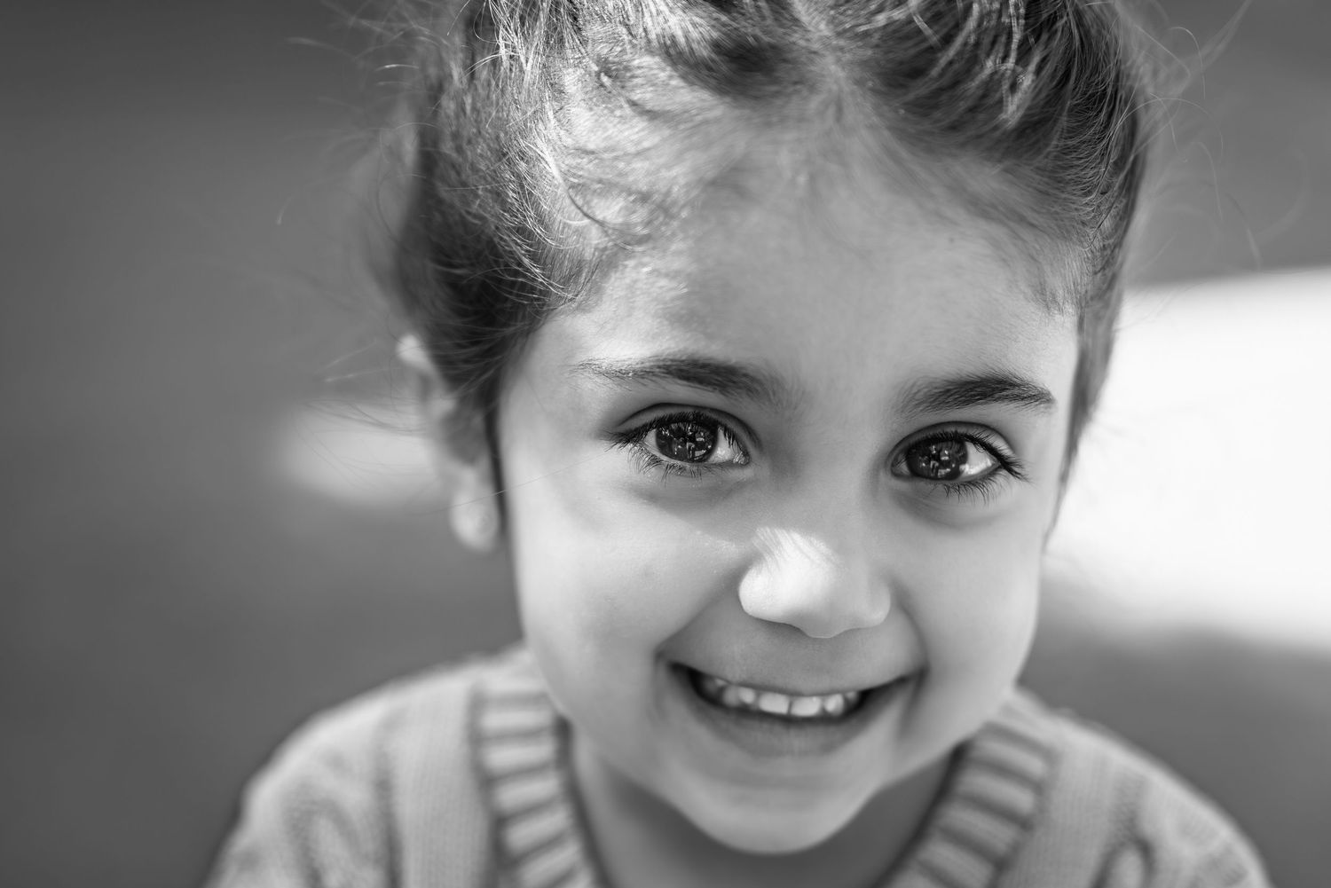 A close up black and white portrait showing bright eyes and a warm smile.