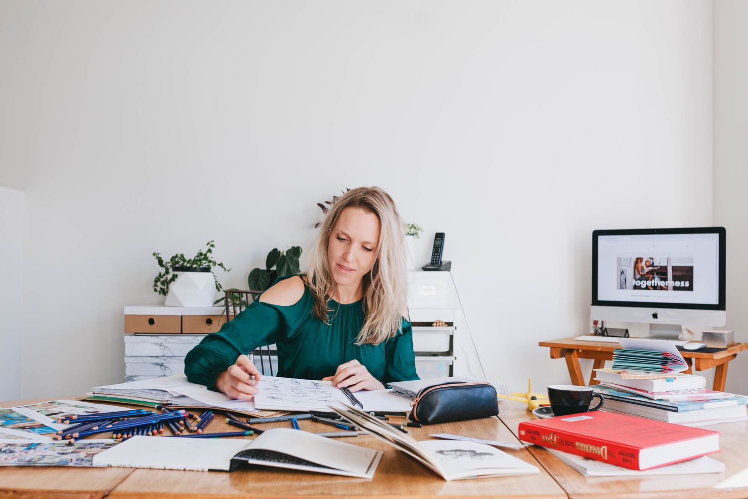 Study scene with books and papers spread across white desk in minimalist setting.