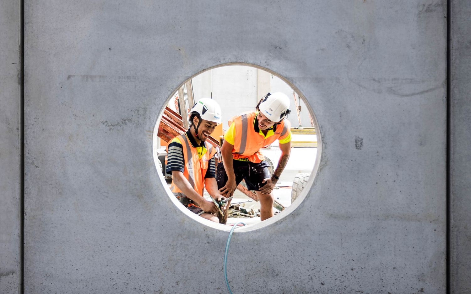 View through circular openings in concrete walls showing construction progress by Maycroft.