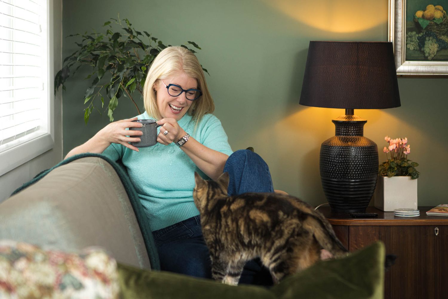 Homes with Soul owner with her cat, desk lamp, and green accent wall.
