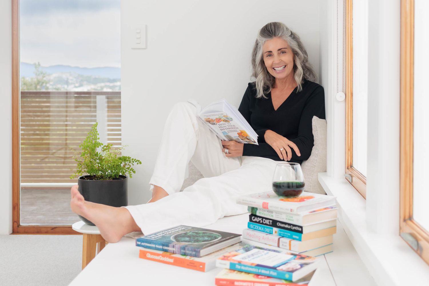 Jo Williment of Sage Studio relaxing with books and glass of wine.