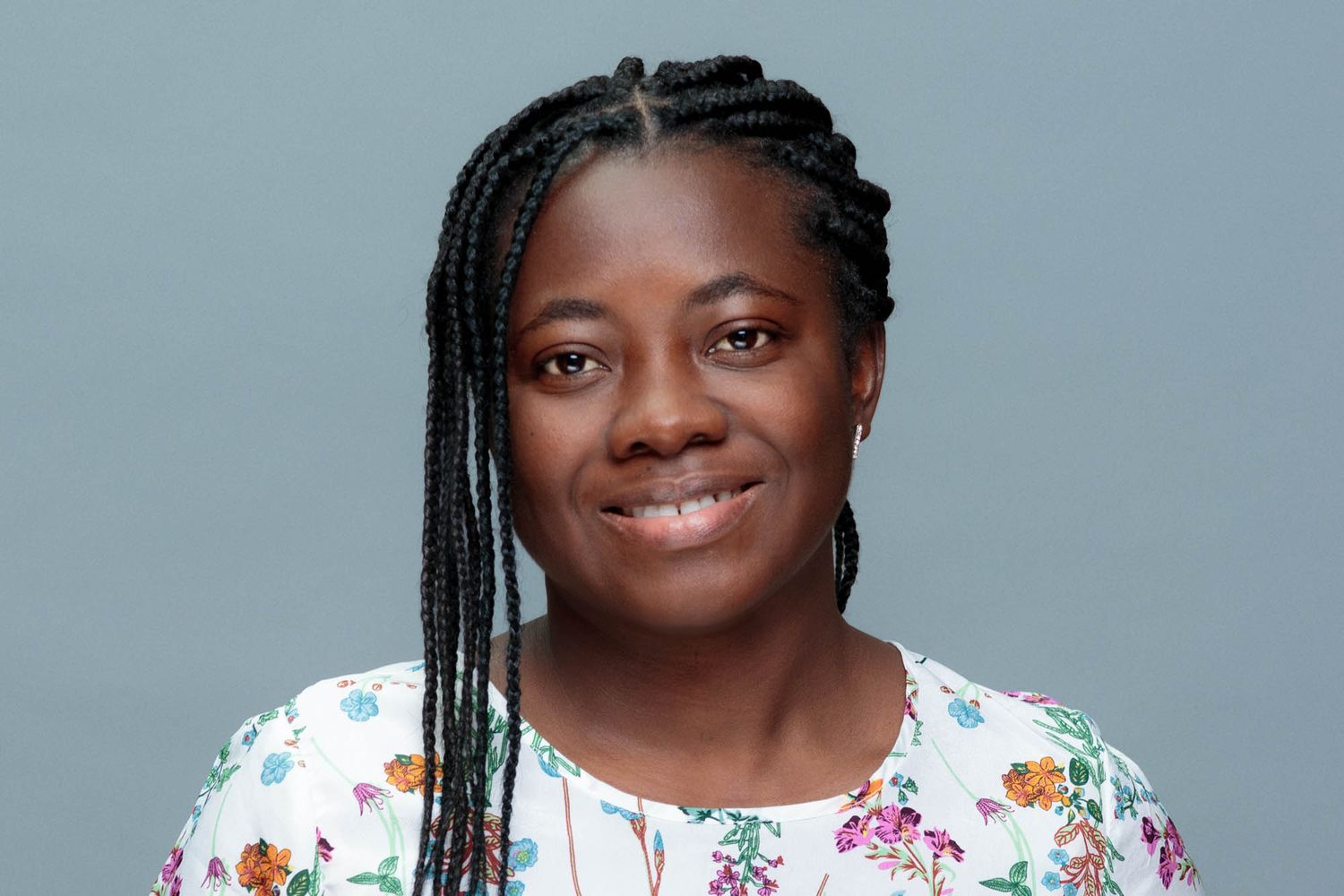 Professional portrait against grey background wearing floral print top.