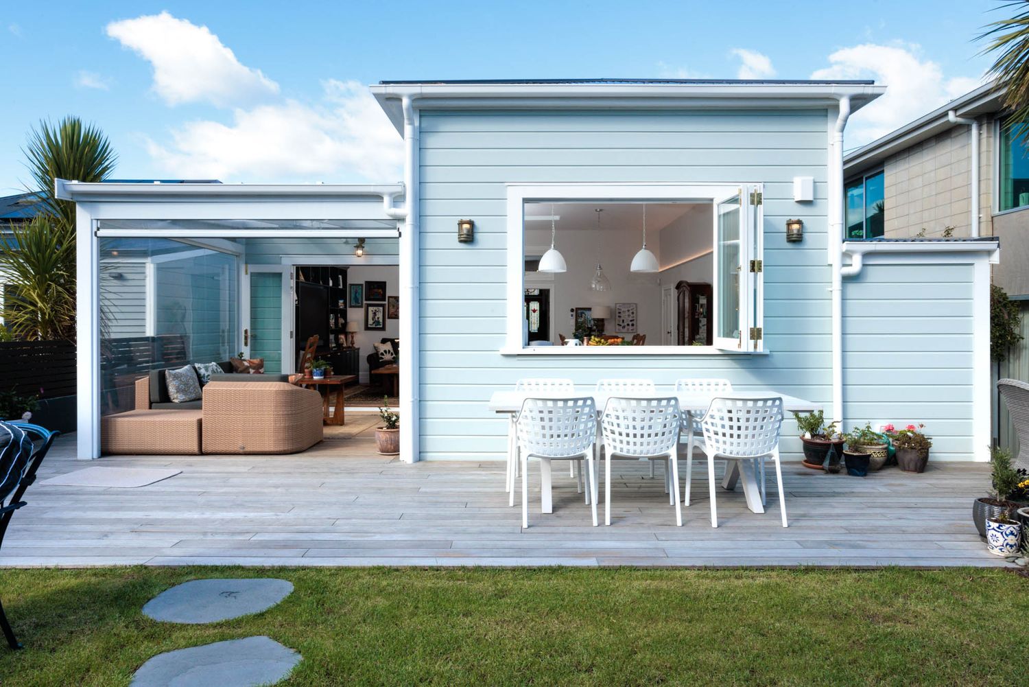 Contemporary coastal home exterior with blue siding and white trim featuring multiple outdoor living spaces.