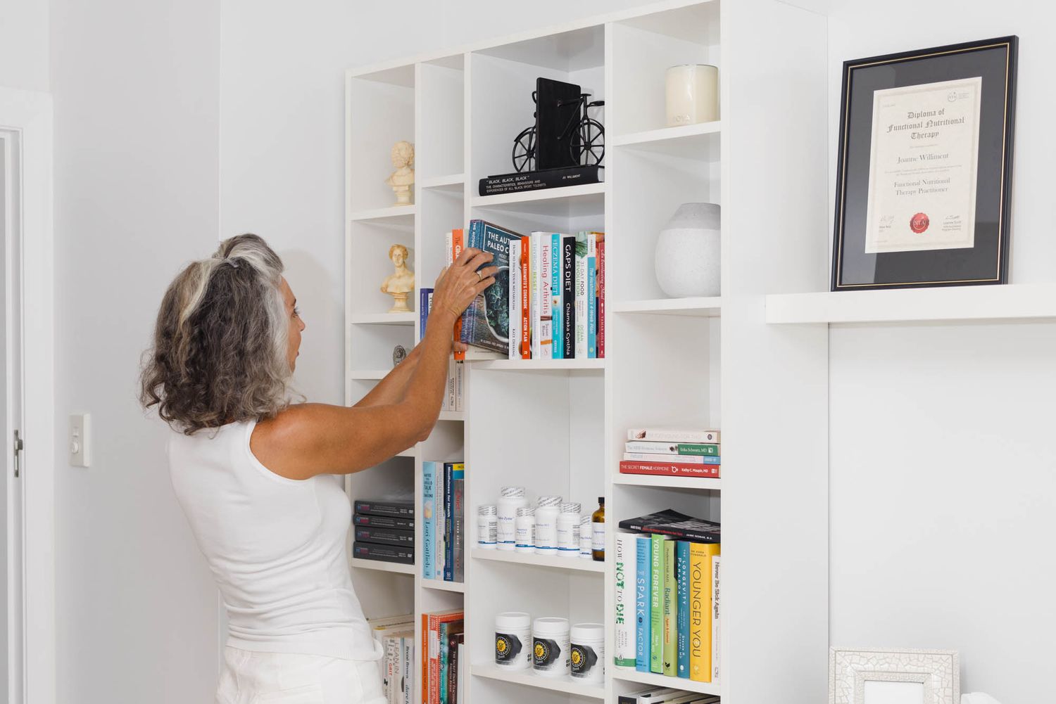 Clean white home interior with built-in bookshelves and wooden window frames.