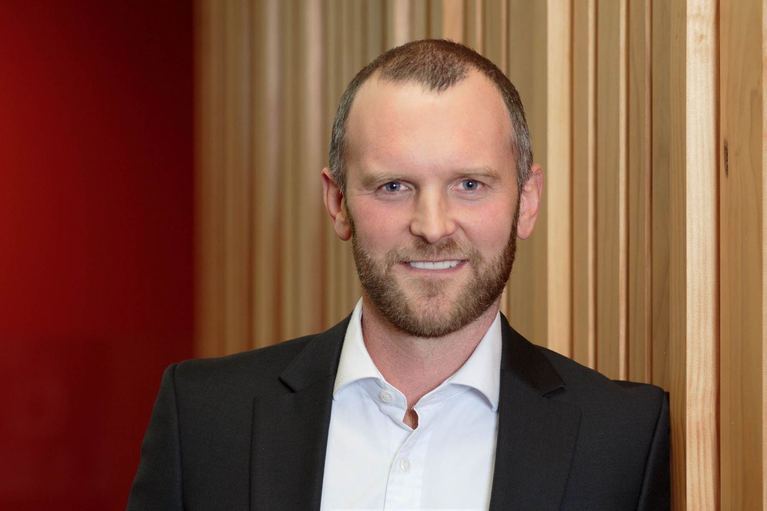 Business portrait of Kelvin Davidson in dark suit against warm-toned background.
