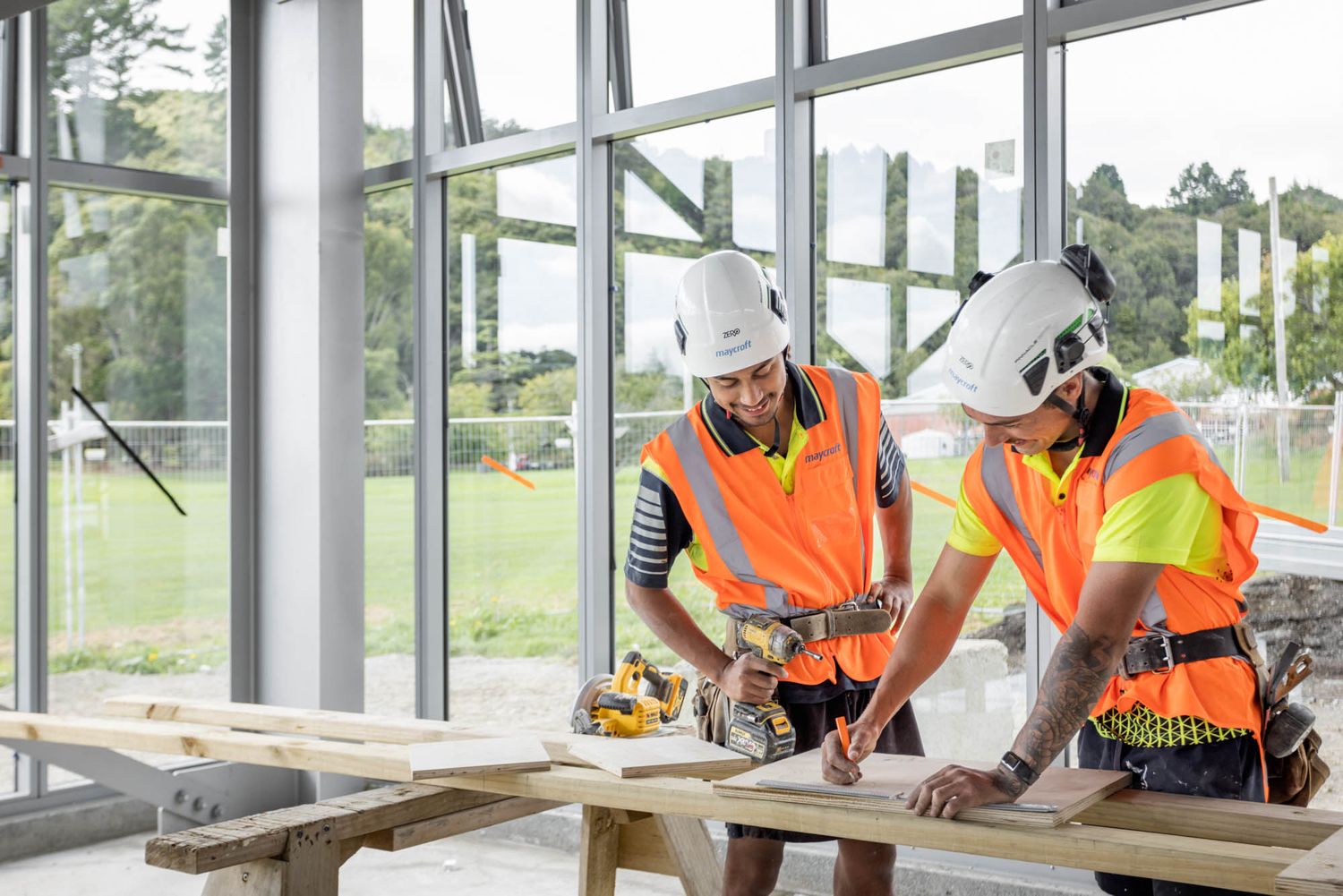 Maycroft construction team reviewing building plans in a bright, window-lined workspace.