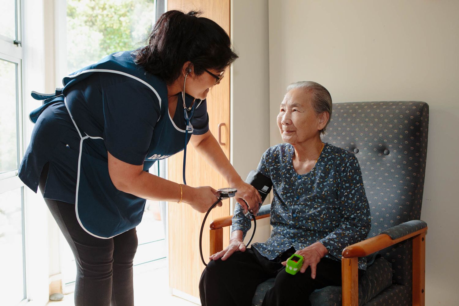 Healthcare worker interacting with residents in a comfortable living room setting.