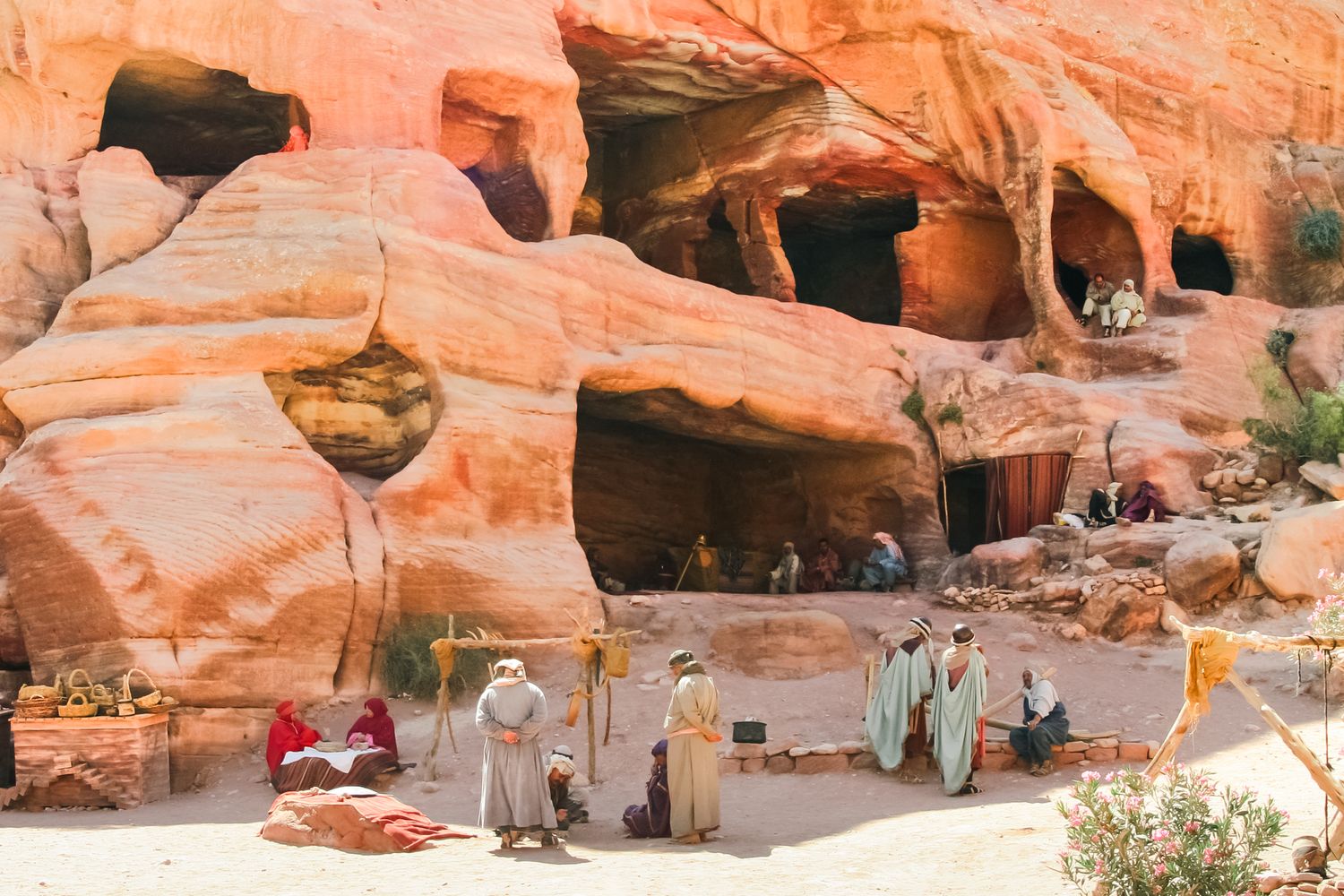 Red sandstone cliffs and rock formations in Petra with tourists exploring.