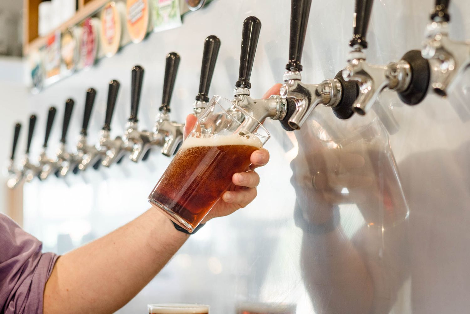 Close-up of stainless steel beer taps in a row at a bar counter.