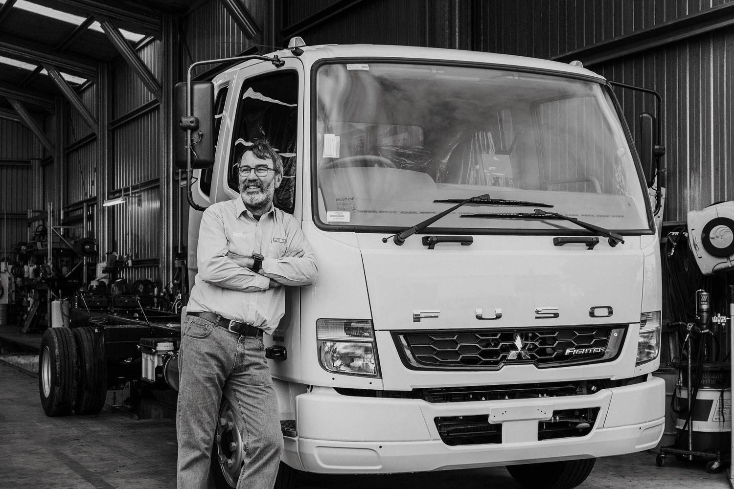 White service van parked inside a commercial auto repair facility.