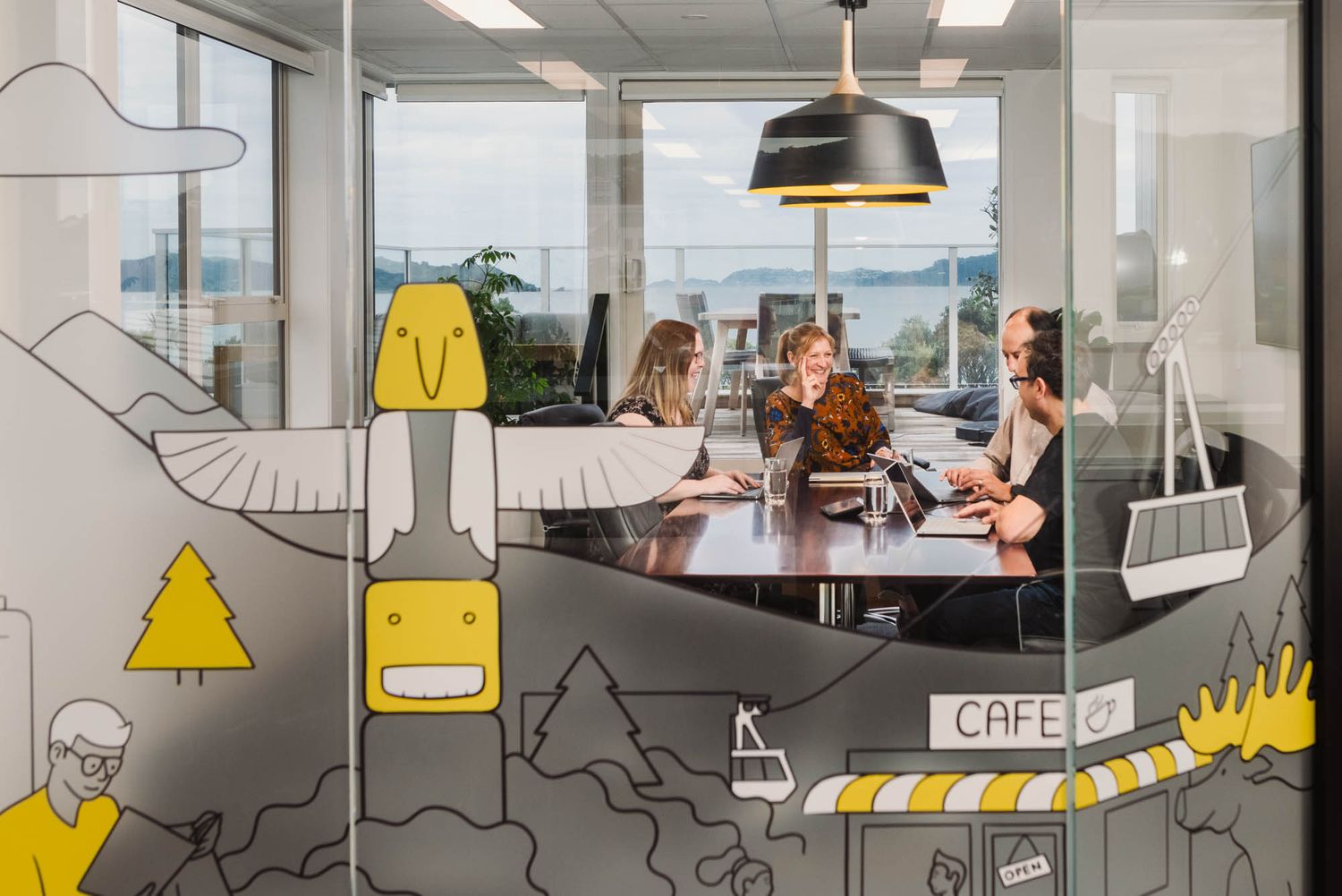 Modern office space at Arlo with decorative wall art featuring yellow and black illustrations.
