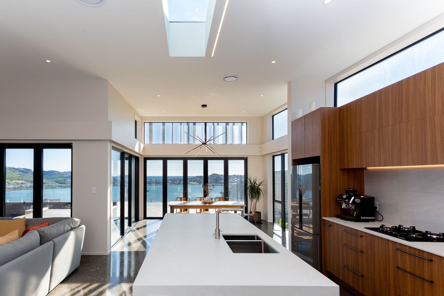 Minimalist open-plan living space with panoramic ocean views and wood accent walls.