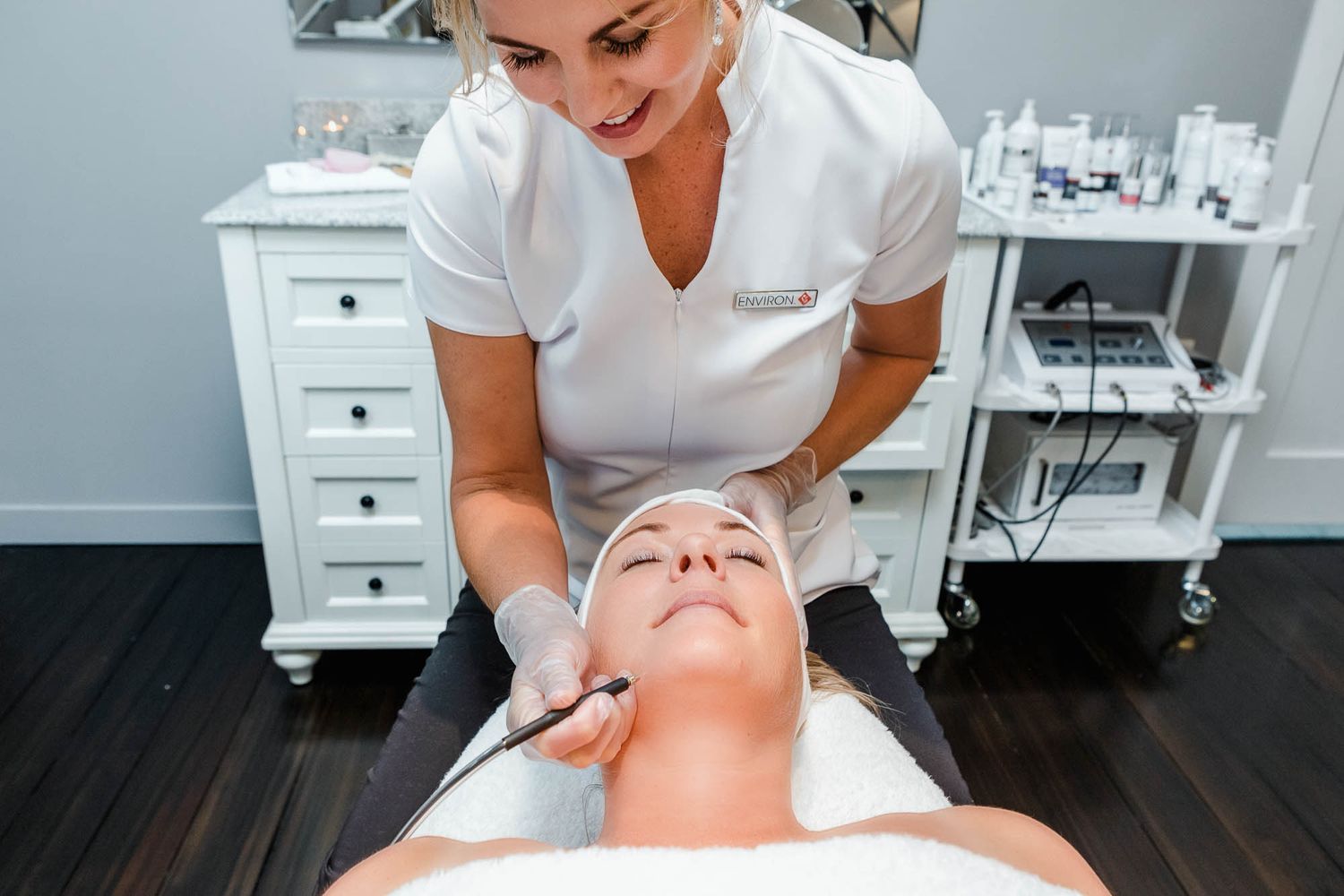 Esthetician performing a facial treatment on a relaxed client in a modern spa salon.