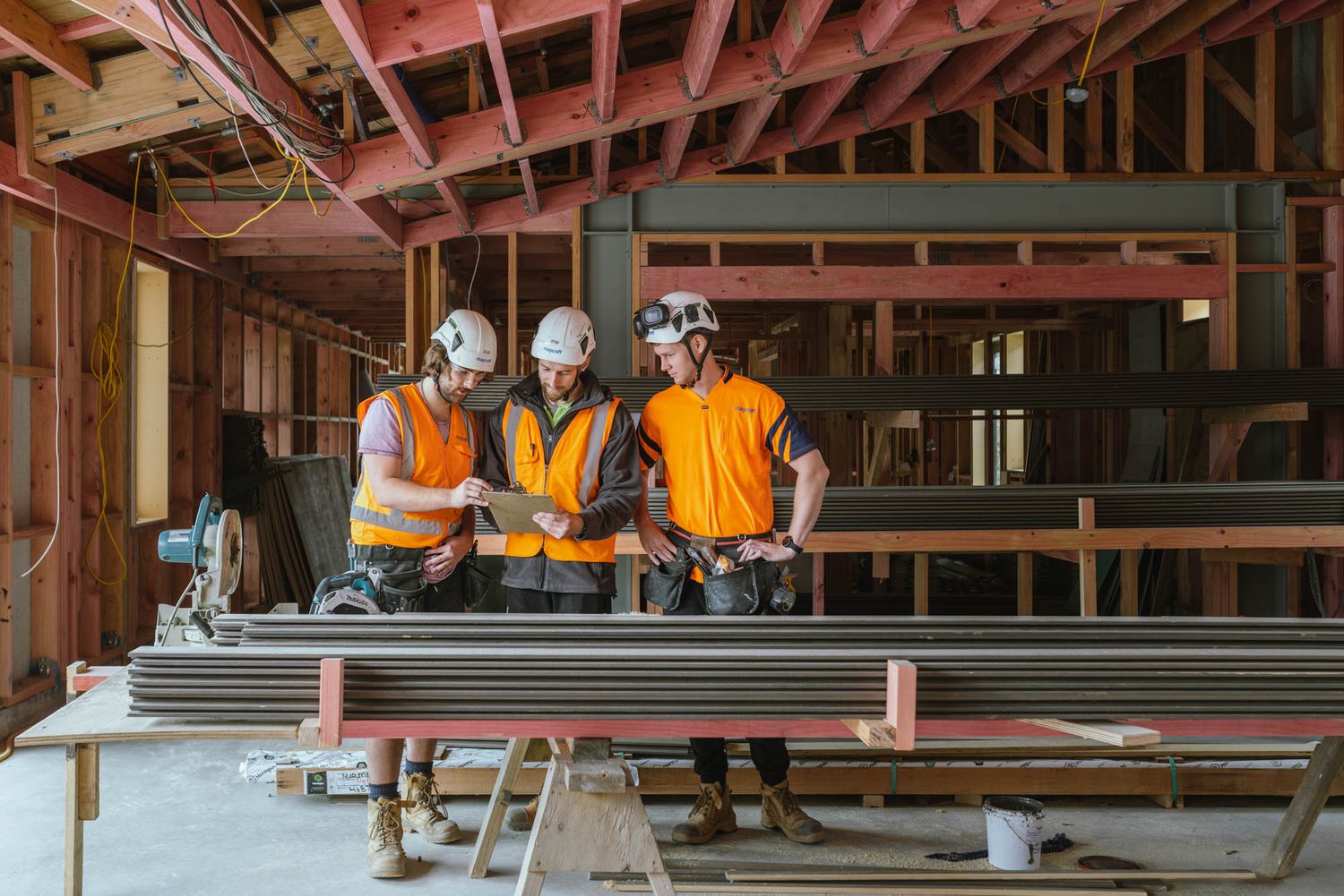 Maycroft construction site interior with exposed beams and workers installing metal framing.