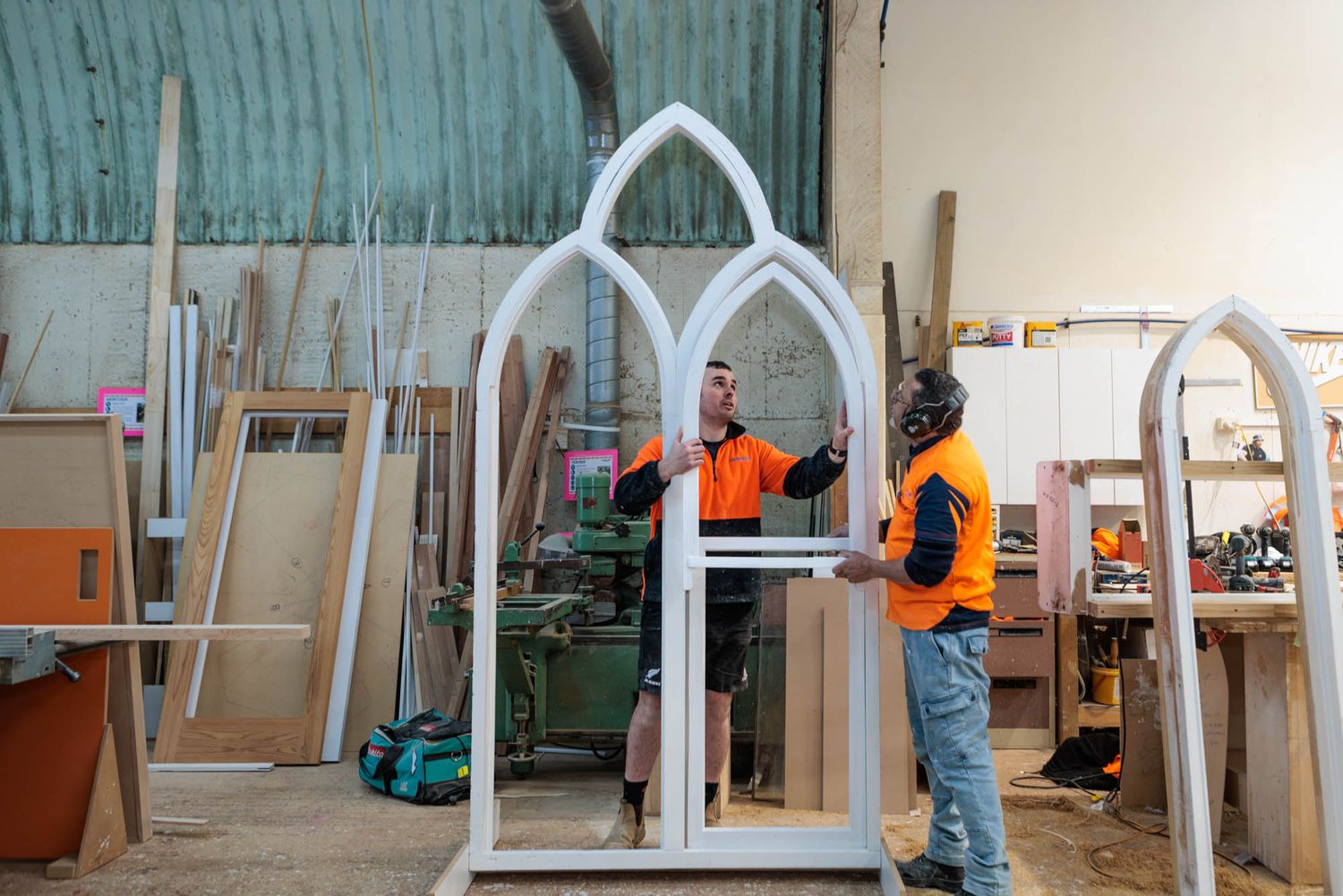 Maycroft workers in safety gear assemble architectural elements in an indoor construction space.