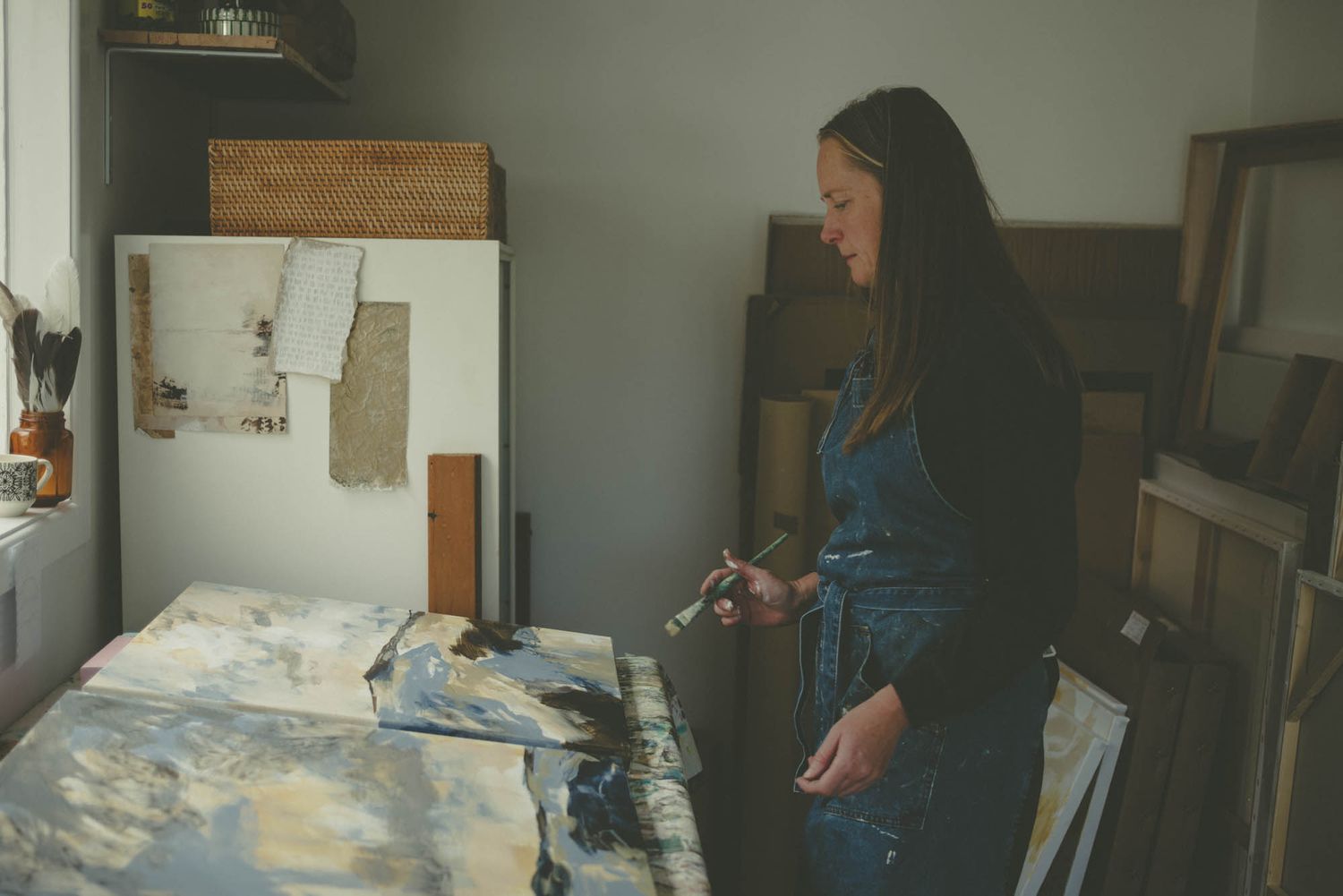 Artist working at a paint-covered table in a studio space.