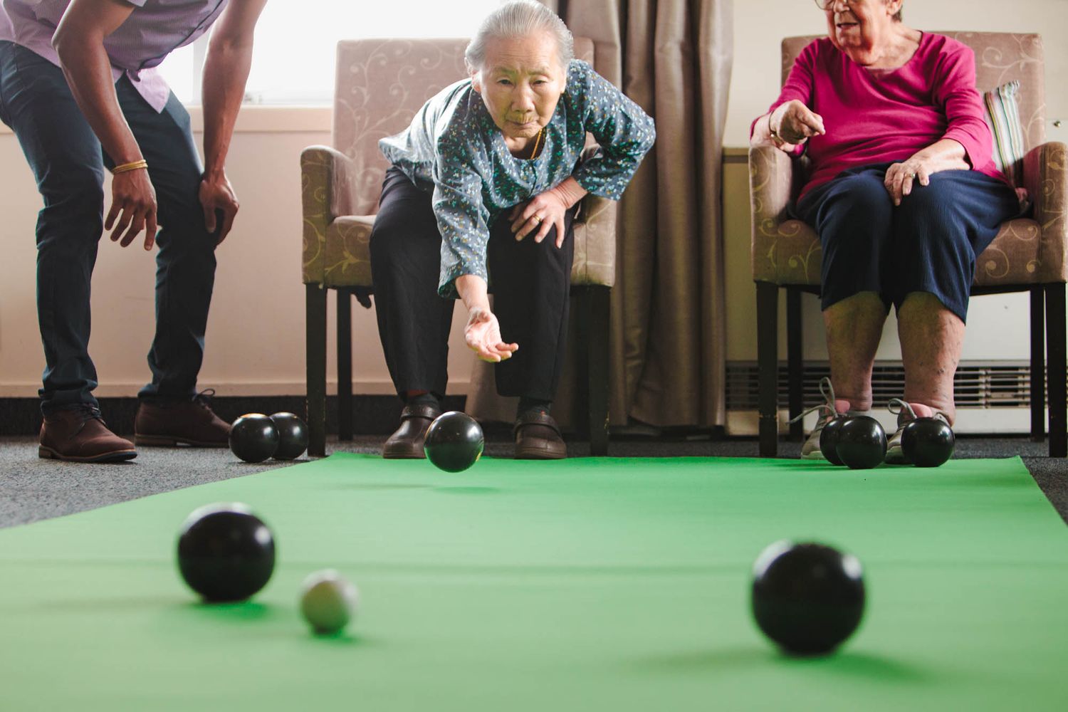 Indoor bowling activity on green carpet with black bowling balls.