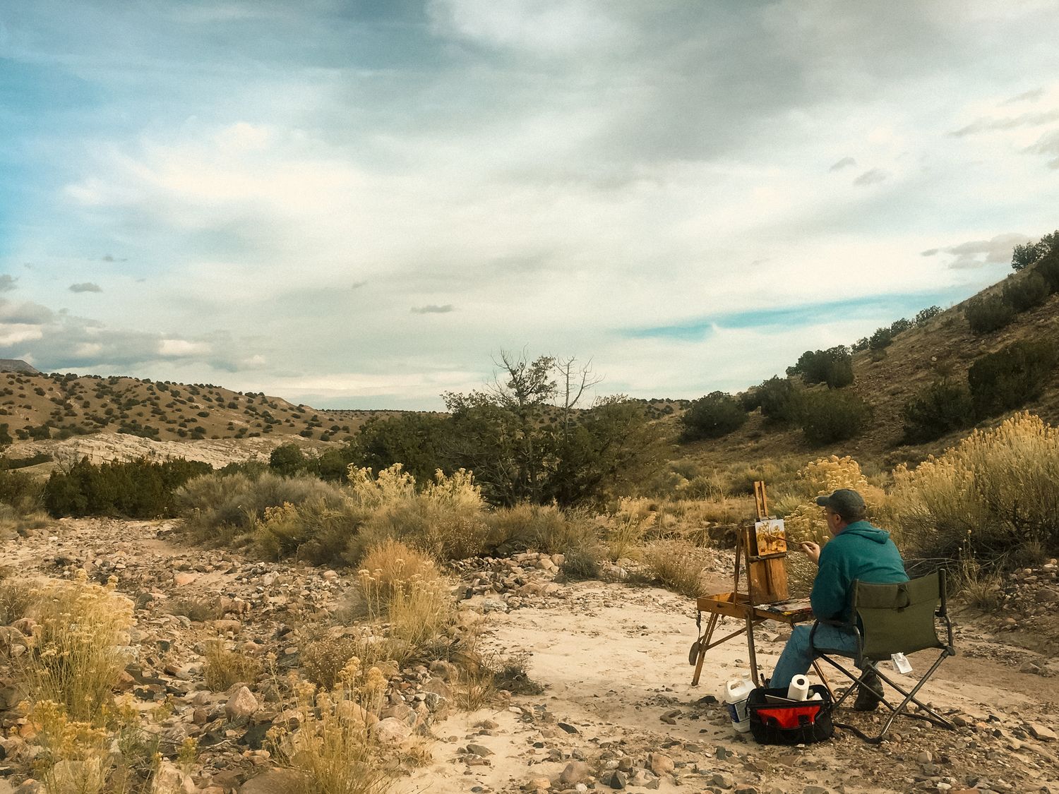 New Mexico desert landscape with camping equipment and sparse vegetation under cloudy skies.
