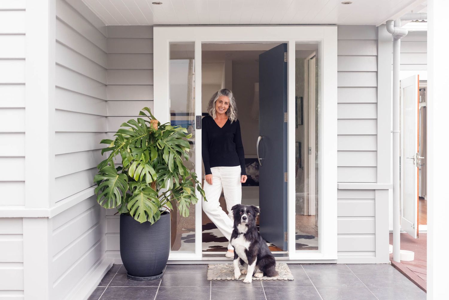 Jo Williment with her dog at the white exterior entrance of her home.