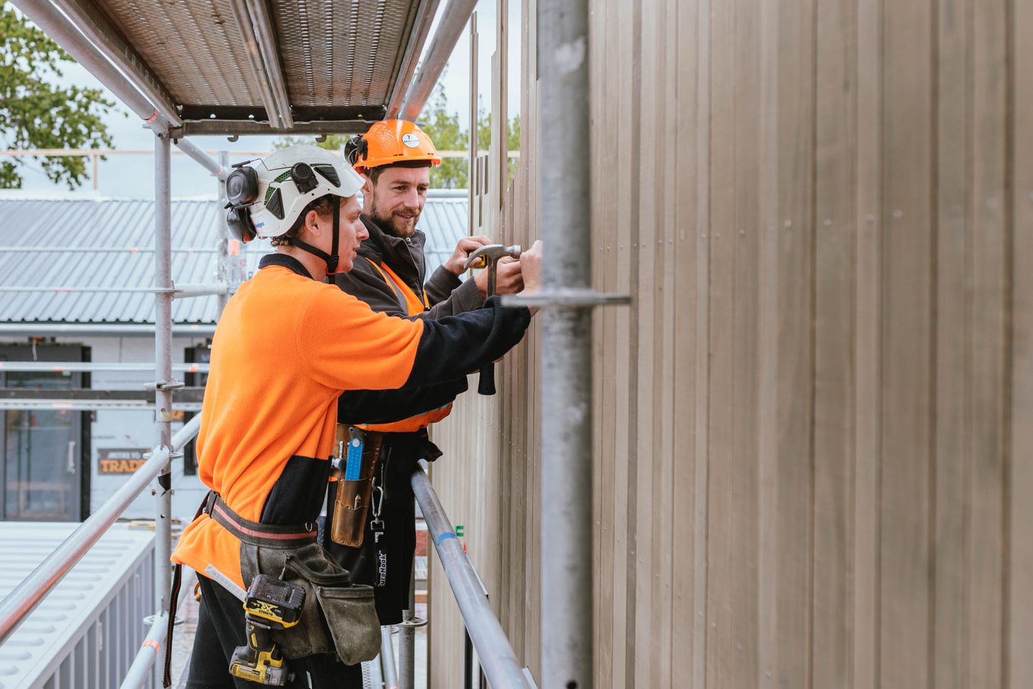Maycroft construction crew in high-visibility gear working on structural supports at a building site.
